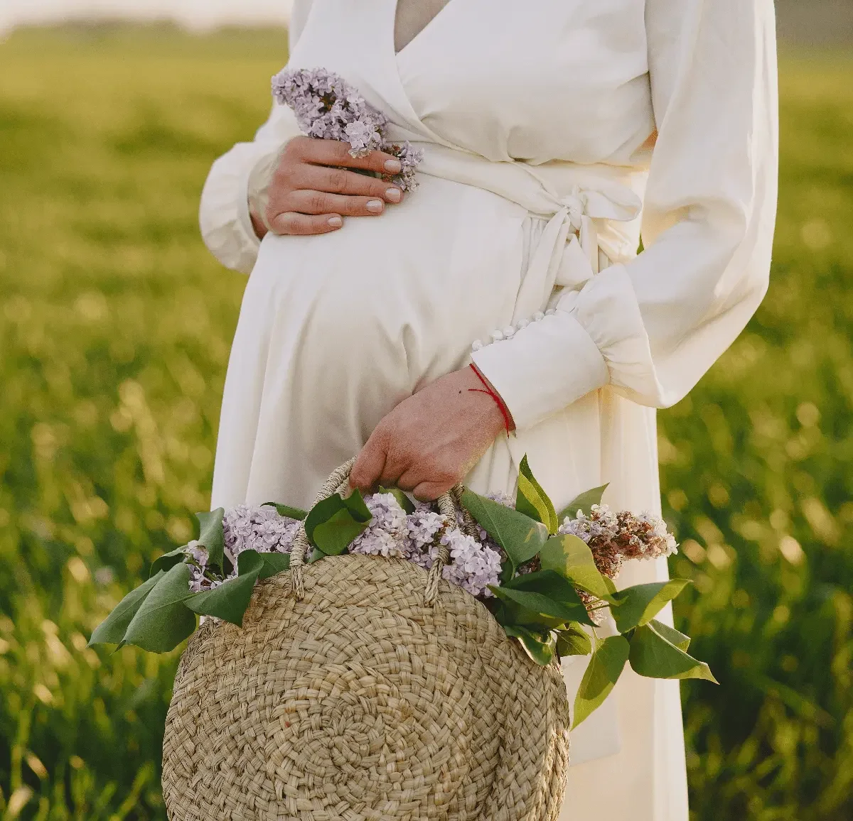 Pregnant woman holding flowers and resting a hand on her belly