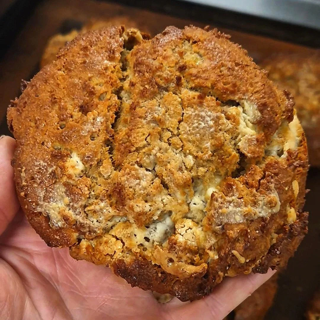 A close-up of a golden, chewy tahini miso cookie with white chocolate chips, showcasing its rich texture and hormone-supportive ingredients like sesame and fermented soy.
