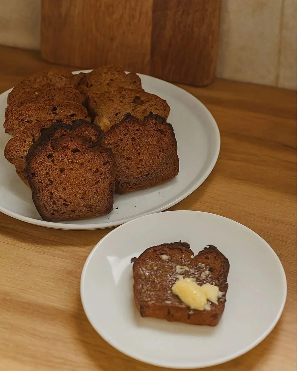 A toasted slice of carrot, zucchini and apple bread with melted butter, placed in front of a plate stacked with more slices of the loaf.