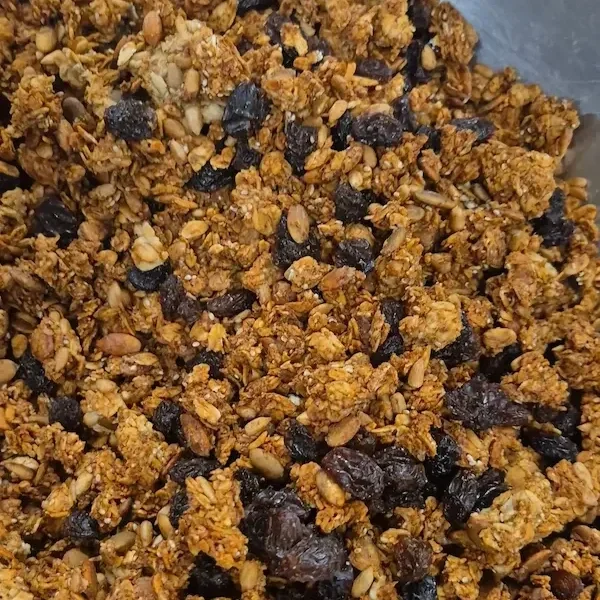 A tray of freshly baked apple pie spice granola mixed with dried fruit, oats, and seeds, golden and crisp straight from the oven for healthy snacking.