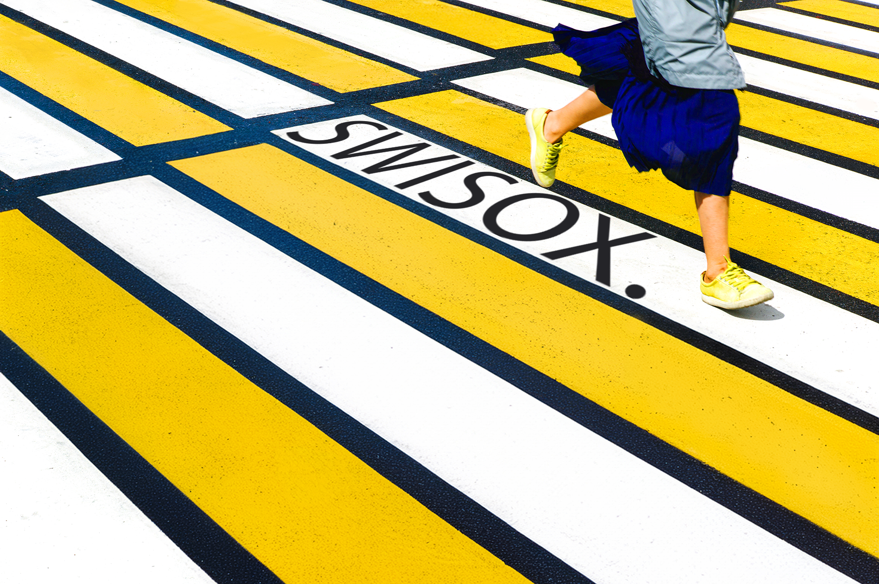 A person wearing yellow shoes and a blue skirt running across a yellow and white striped crossing with 'SWISOX' text.