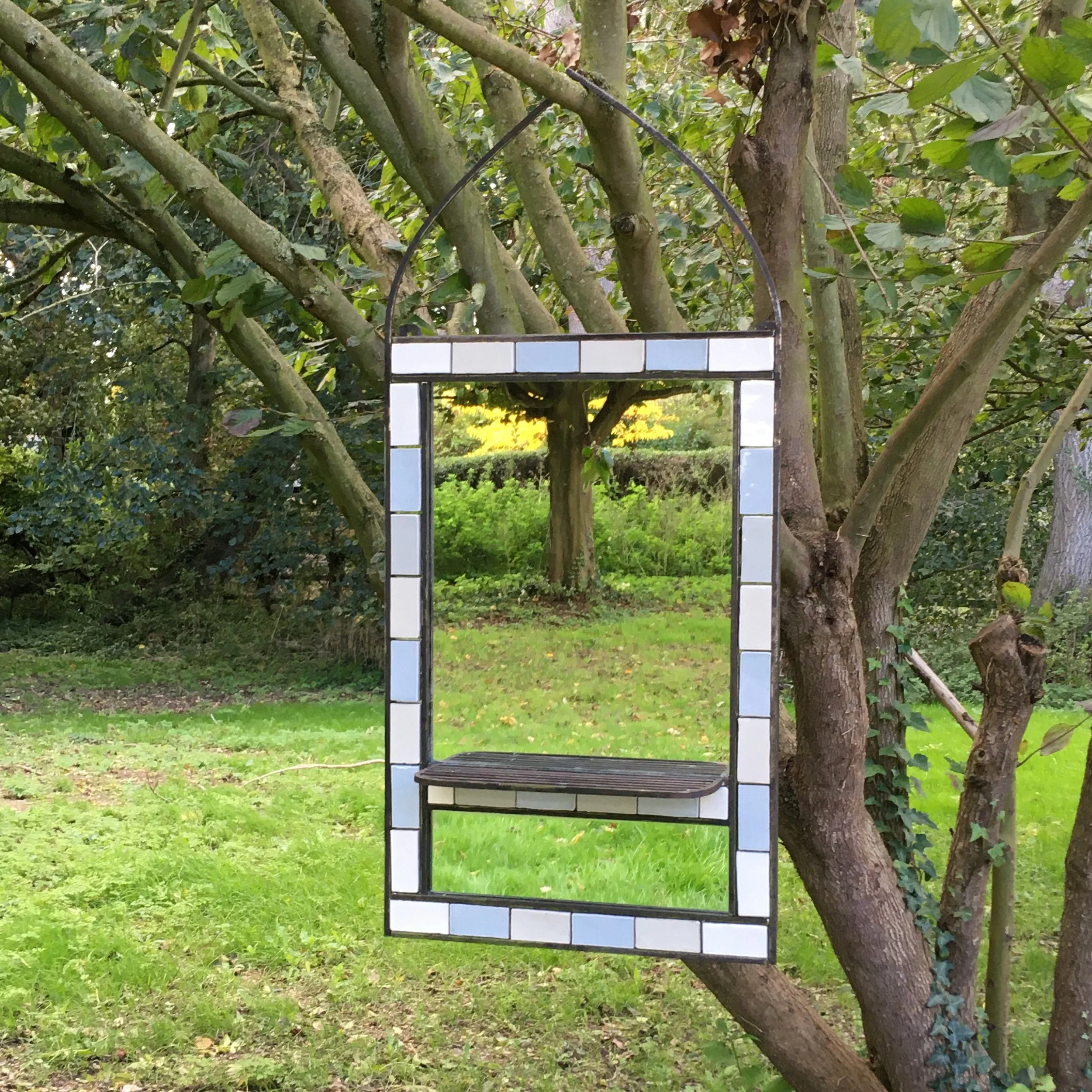 An old mirror turned into a hanging arch way, reflecting the green back to us. 
