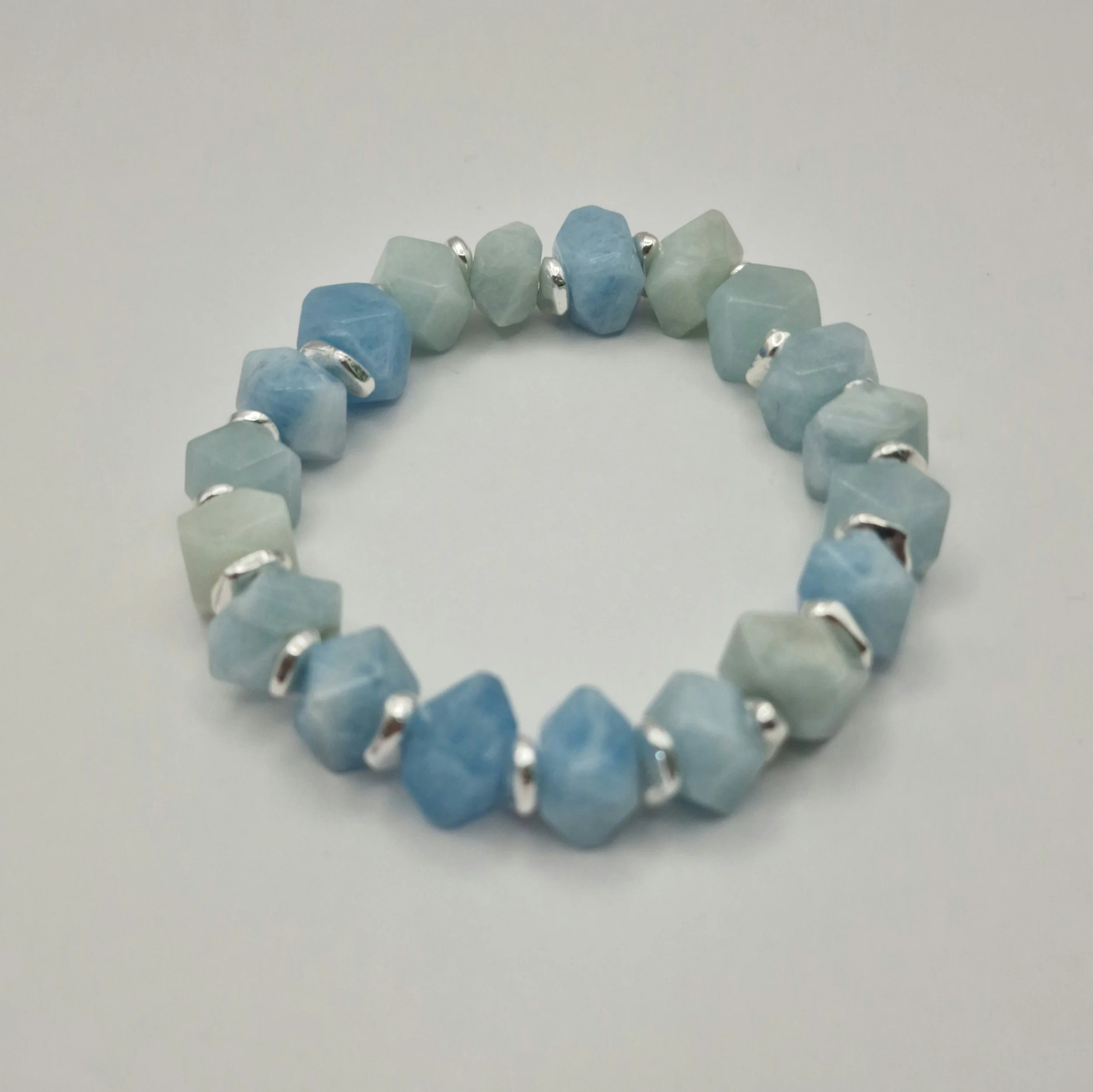 Armband aus unregelmäßigen blauen Aquamarin Perlen mit versilberten Spacern auf weißem Untergrund