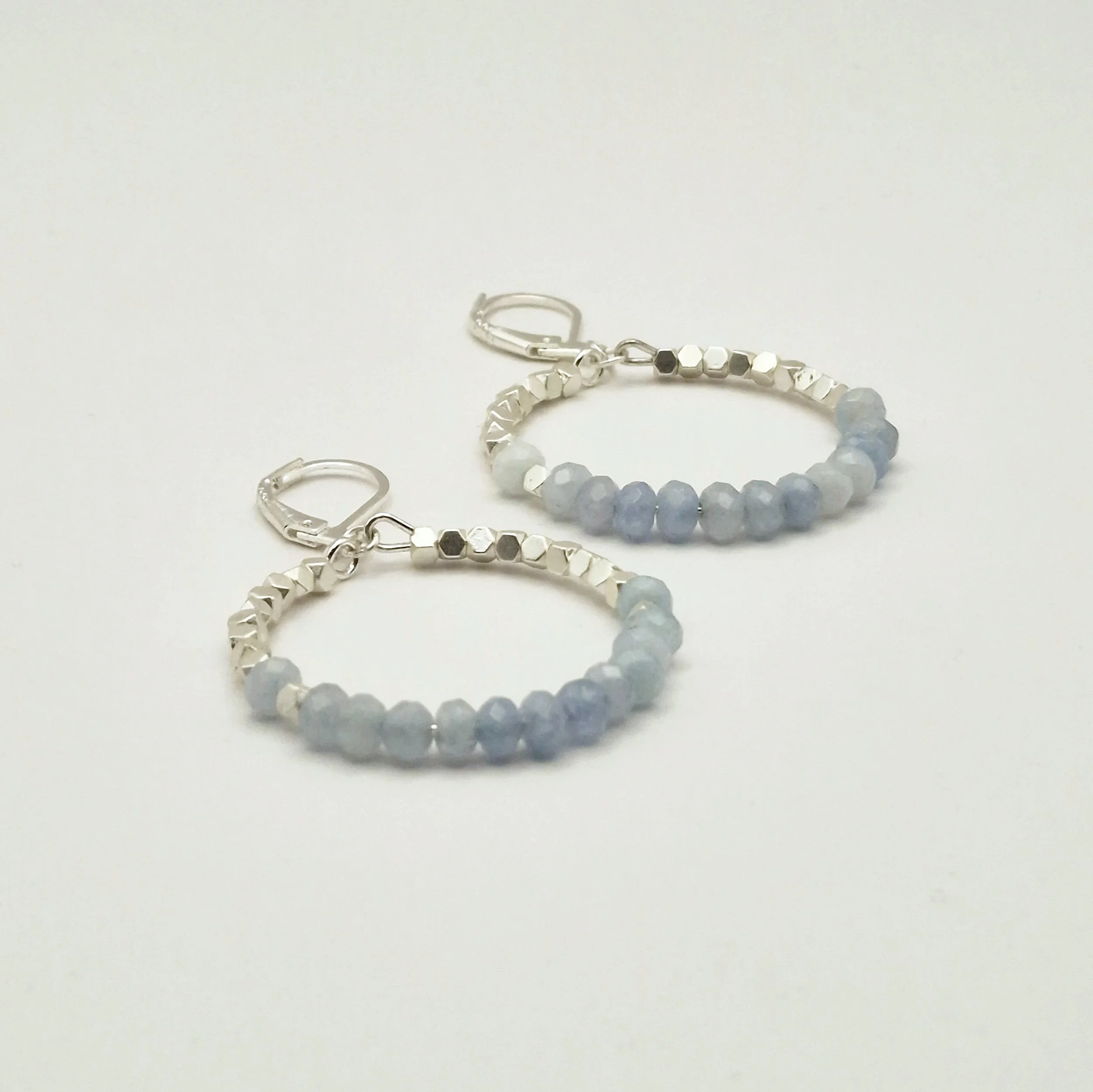 runde Hoop - Ohrringe in Silber mit weißvergoldetem Hämatit Perlen und facettierten Aquamarinperlen auf hellem Untergrund