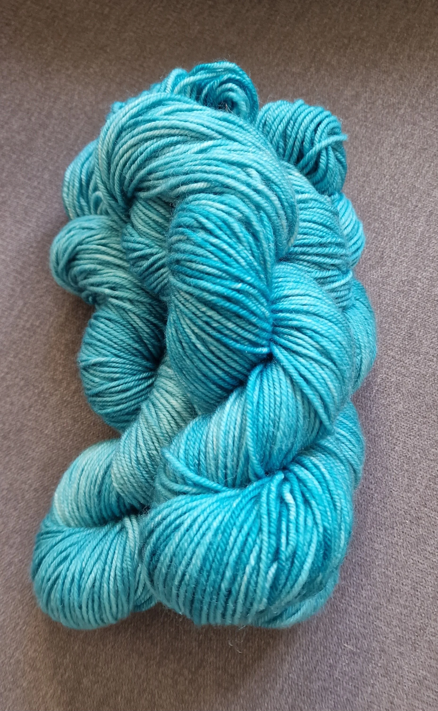 handgefärbte Stränge Wolle in blau auf grauem Untergrund