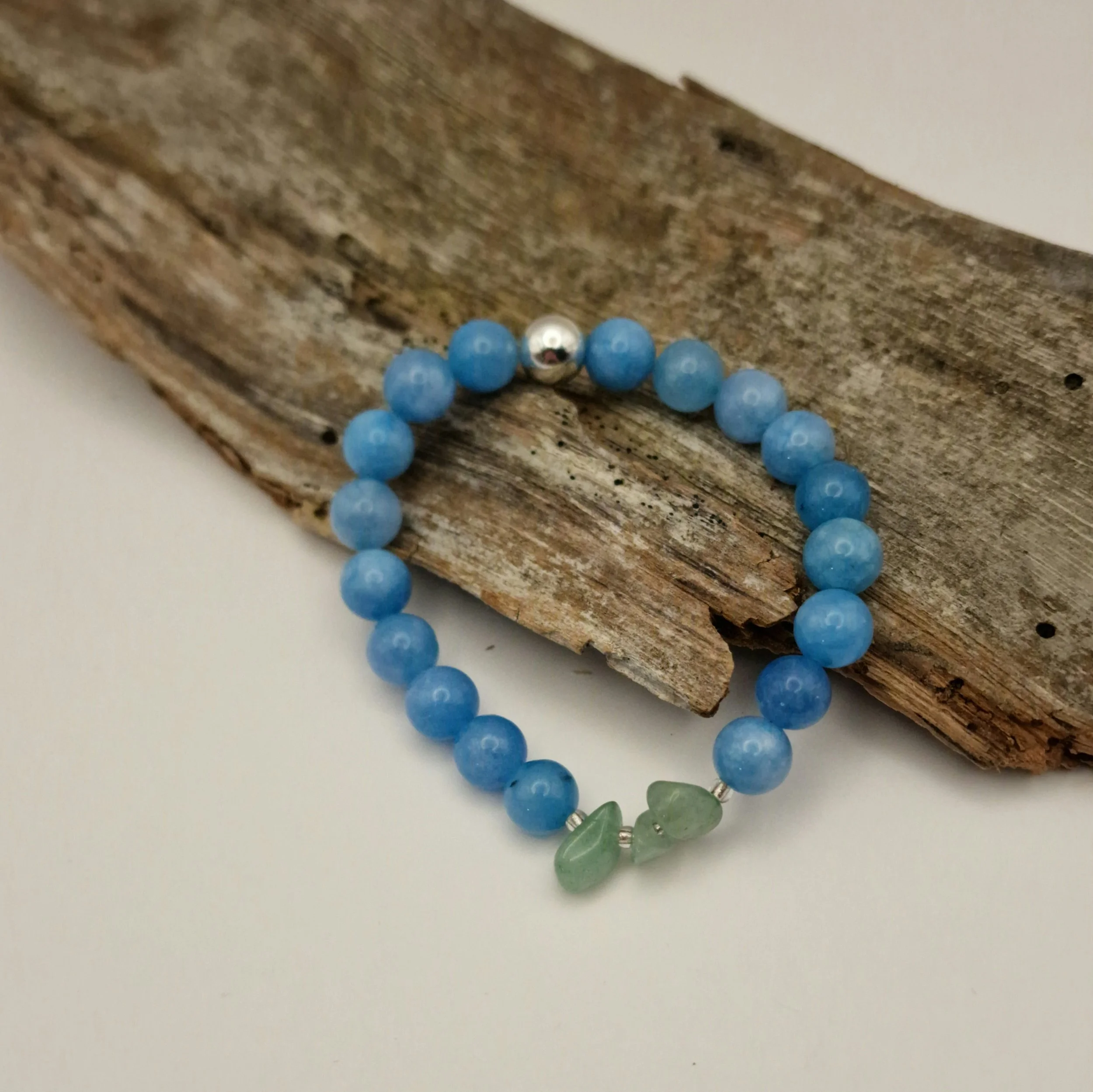 Armband aus blauen Aquamarinperlen mit Amazonitsplittern und einer versilberten Hämatit-Perle auf Treibholz und hellem Untergrund