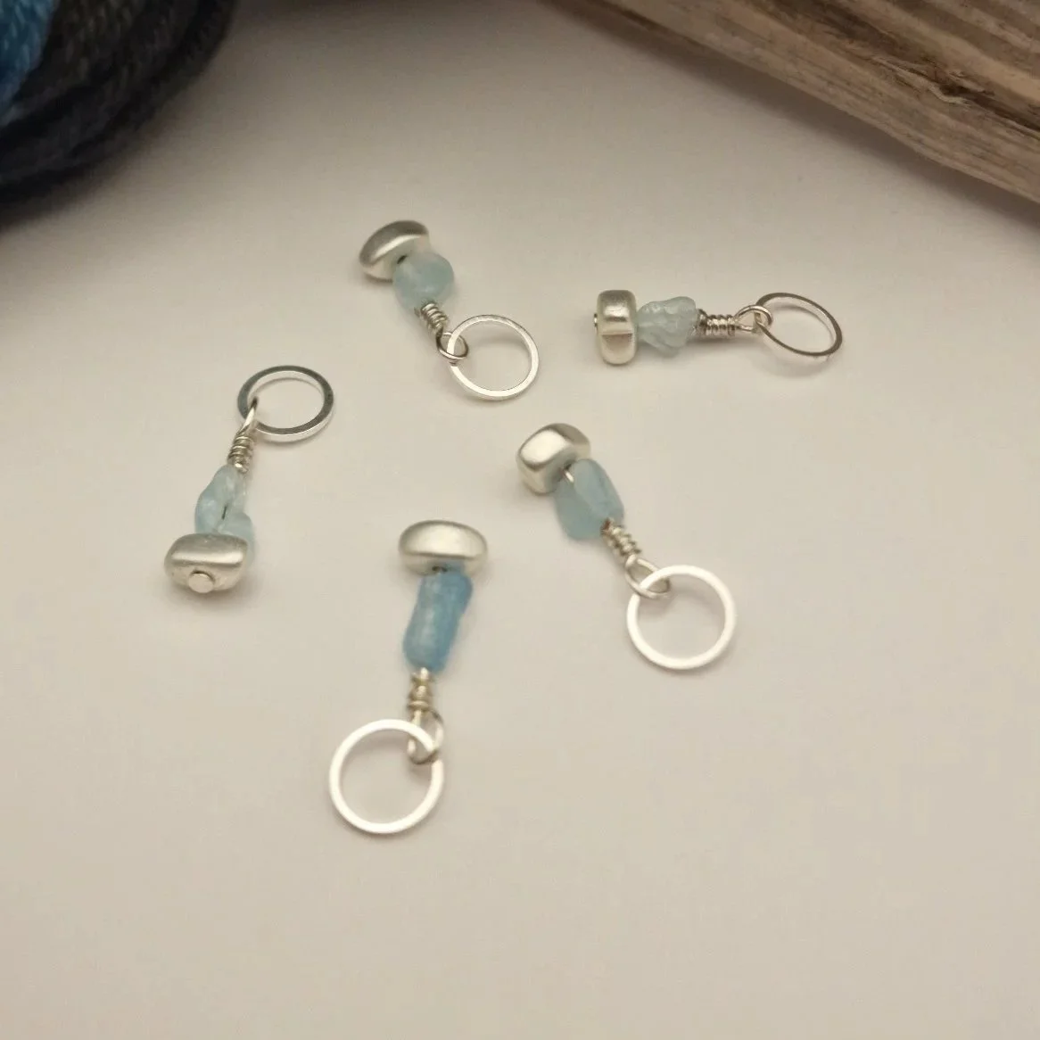 Set von 5 Maschenmarkierern mit Nuggets von Aquamarin und versilbertem matten Hämatit und versilberten Ringen auf weißem Untergrund