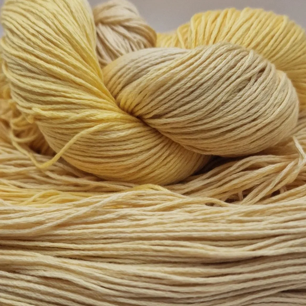 Handgefärbtes Lyocell Garn im Farbverlauf von einem weichen Sandbeige zu einem warmen Gelb auf hellem Untergrund