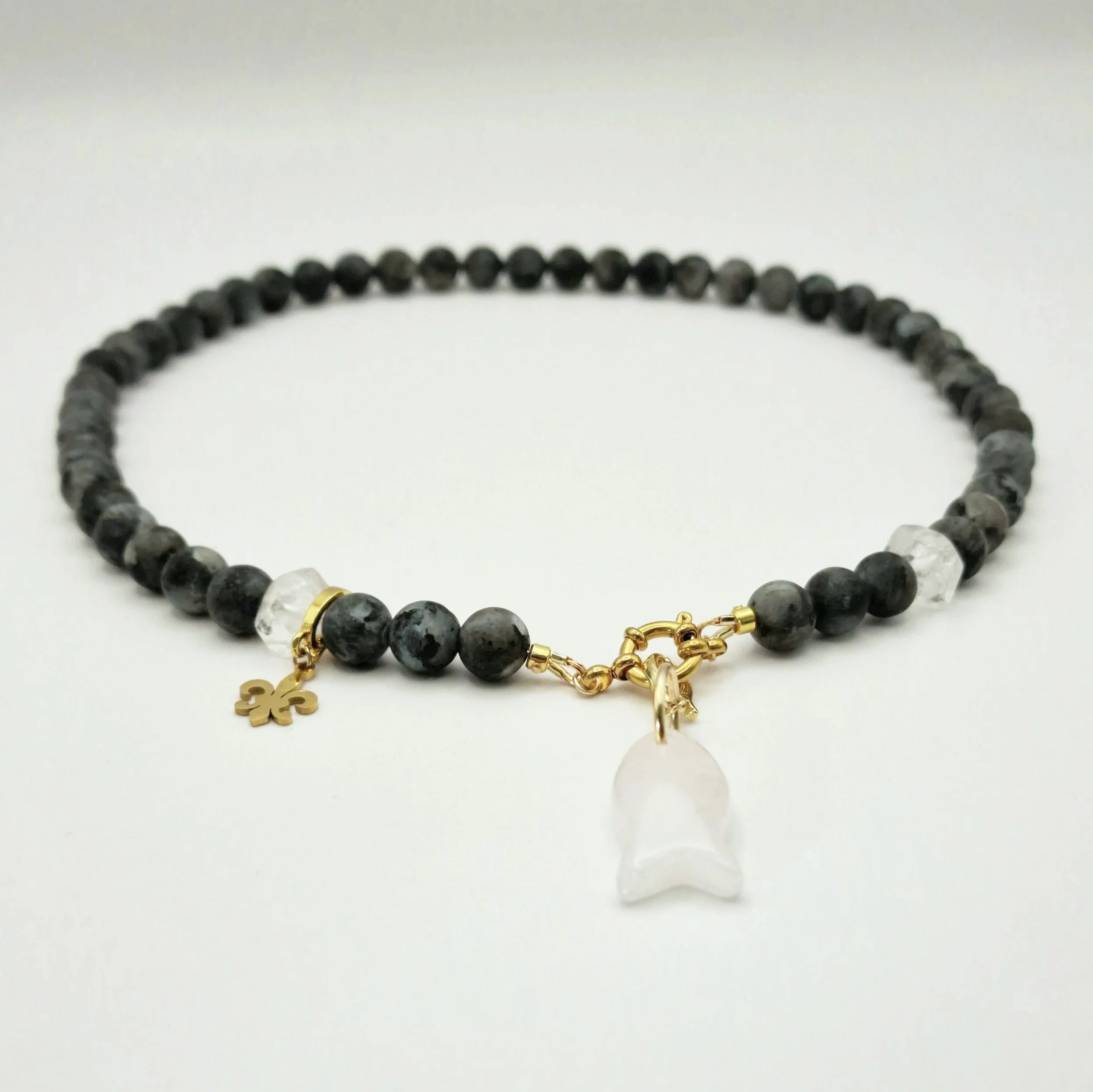 Kette aus Spektrolit, Bergkristall und Rosenquarzanhänger in Fischform mit vergoldetem Verschluss auf hellem Untergrund