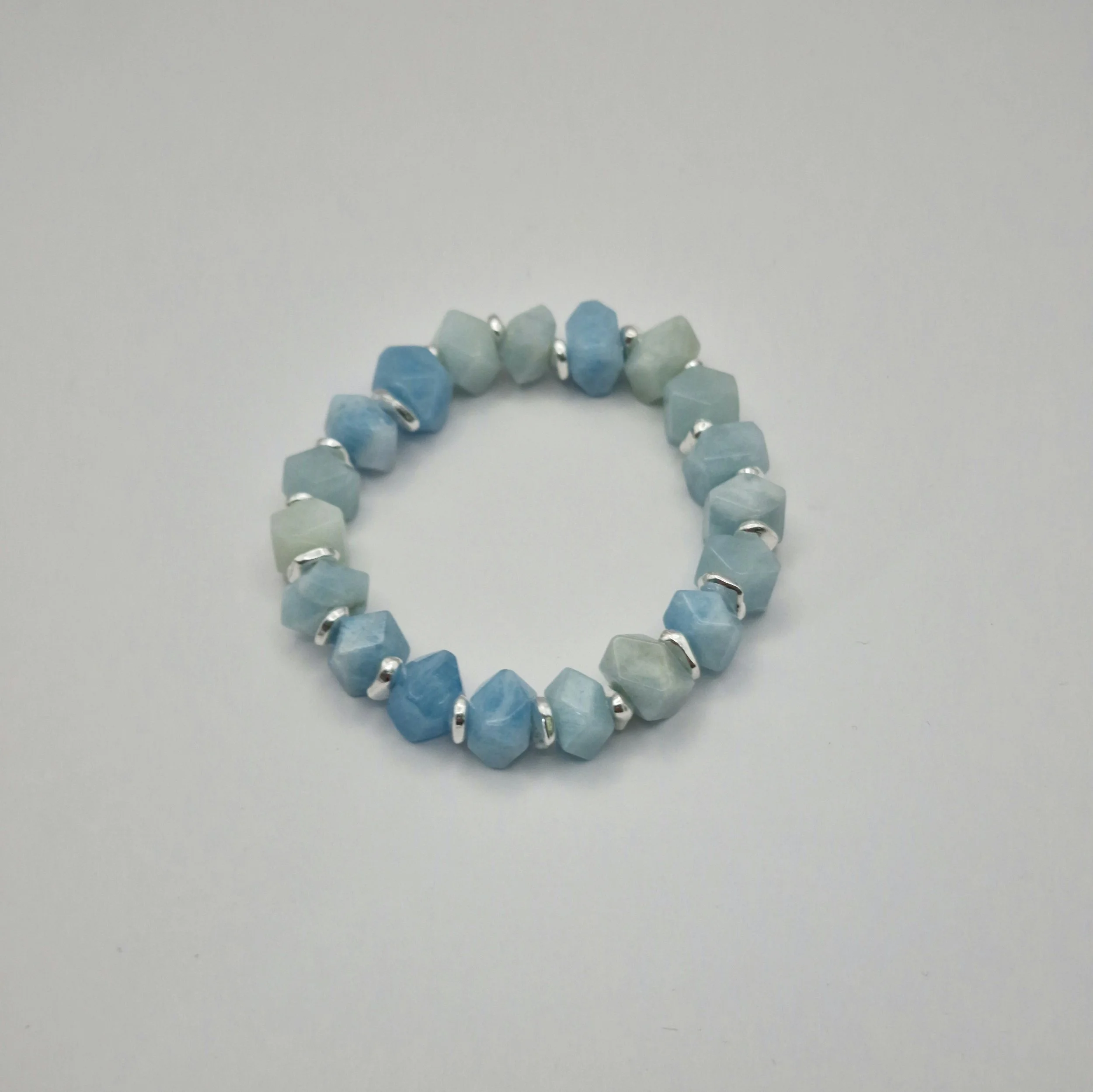 Armband aus unregelmäßigen blauen Aquamarin Perlen mit versilberten Spacern auf weißem Untergrund