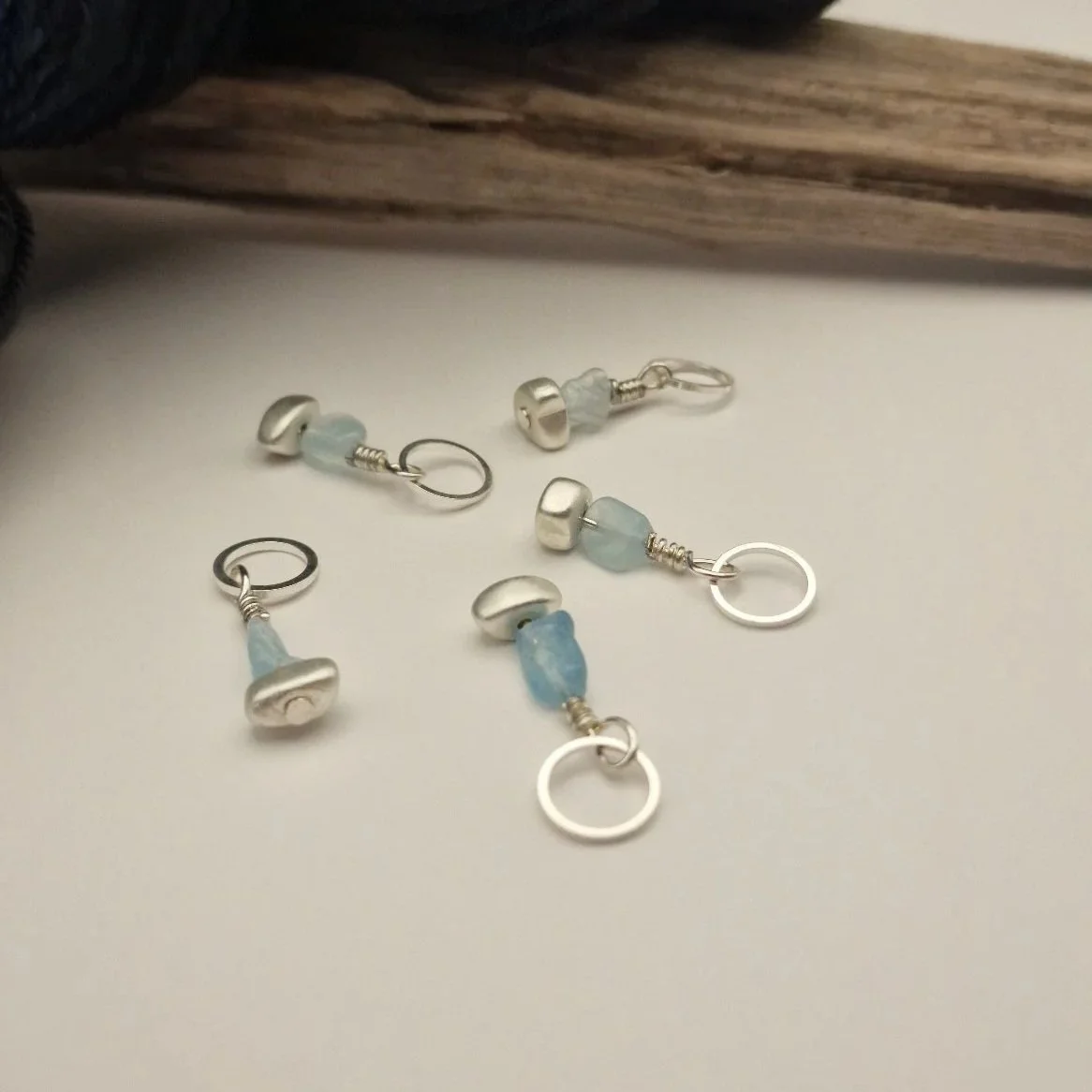Set von 5 Maschenmarkierern mit Nuggets von Aquamarin und versilbertem matten Hämatit und versilberten Ringen auf weißem Untergrund