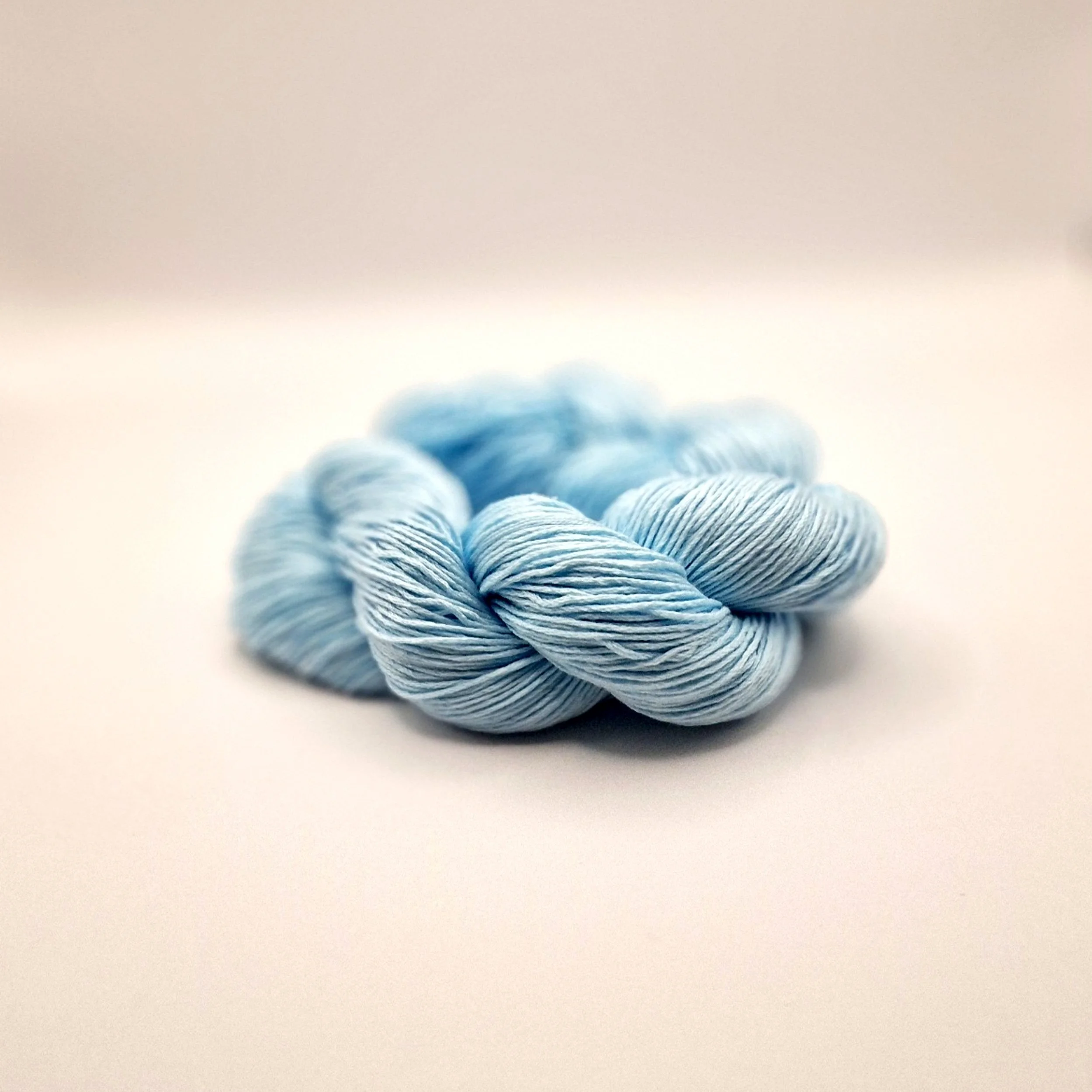 zartblaues Tencelgarn auf hellem Untergrund zu einem Strang gewickelt