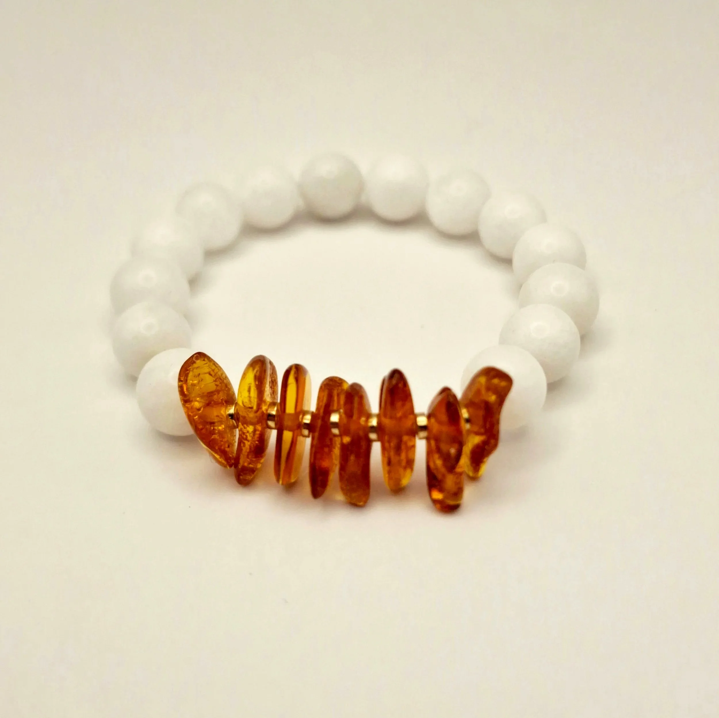Armband aus weißen Perlen und Bernsteinsplittern auf hellem Untergrund