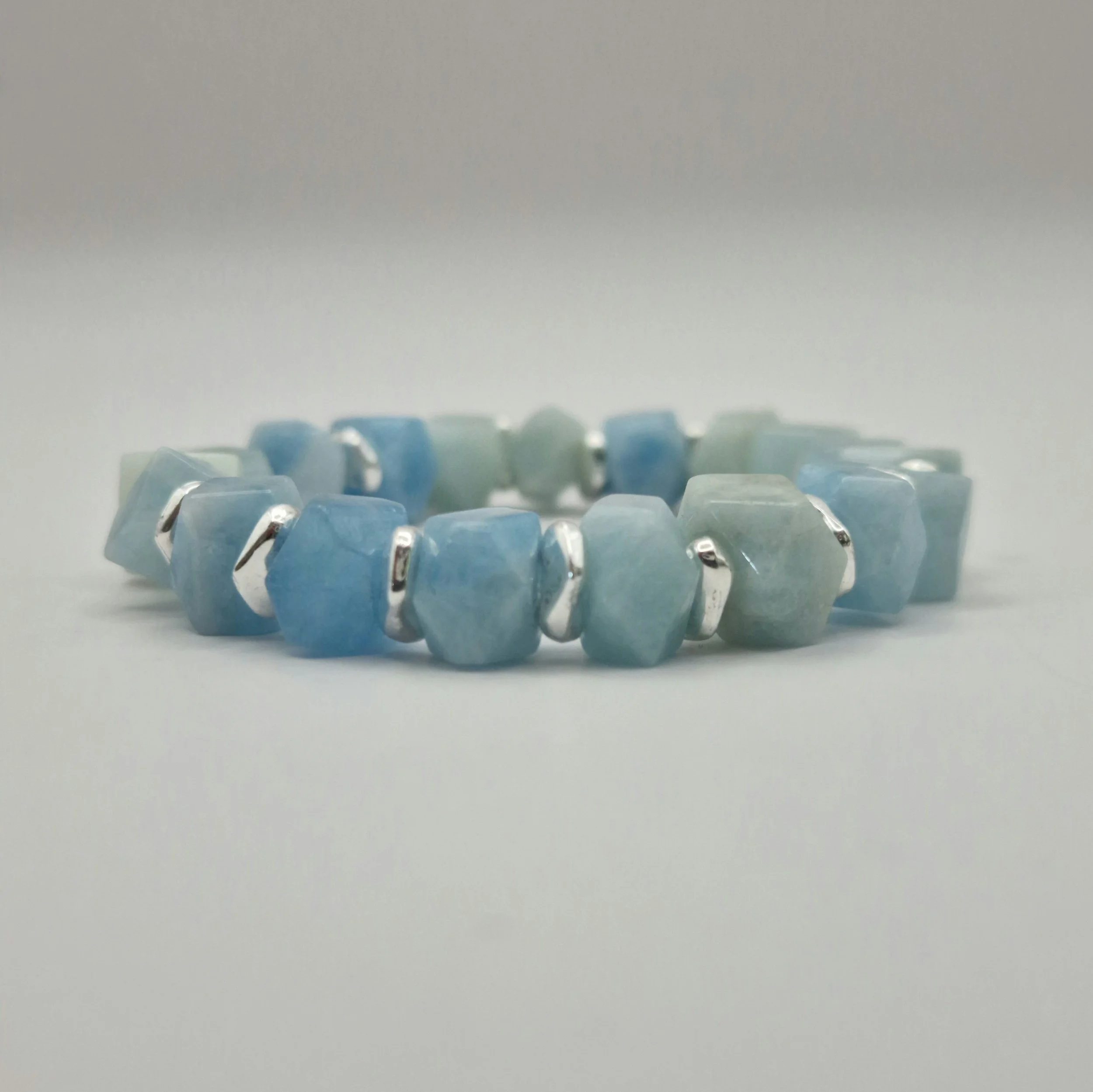 Armband aus unregelmäßigen blauen Aquamarin Perlen mit versilberten Spacern auf weißem Untergrund