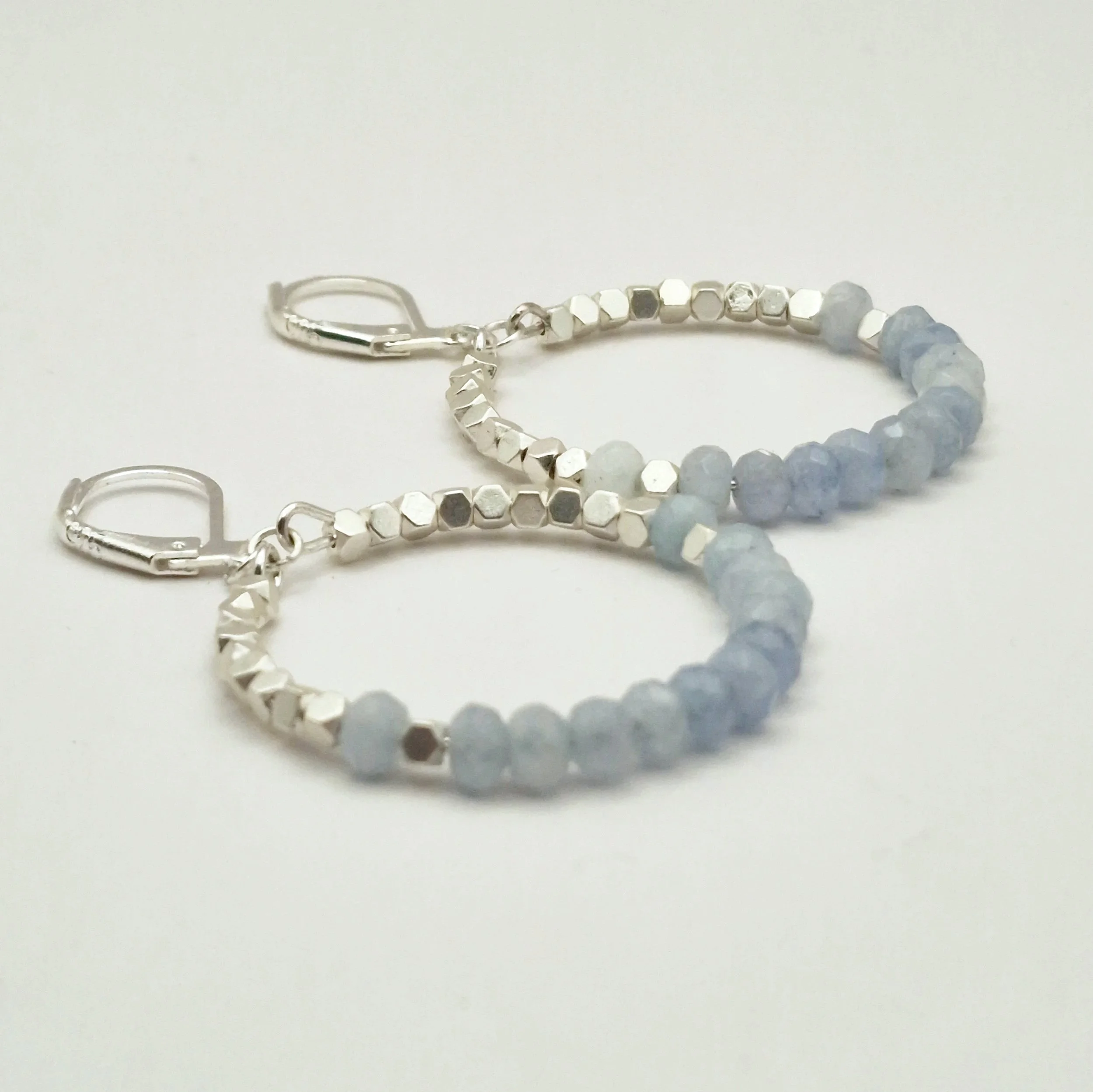 runde Hoop - Ohrringe in Silber mit weißvergoldetem Hämatit Perlen und facettierten Aquamarinperlen auf hellem Untergrund