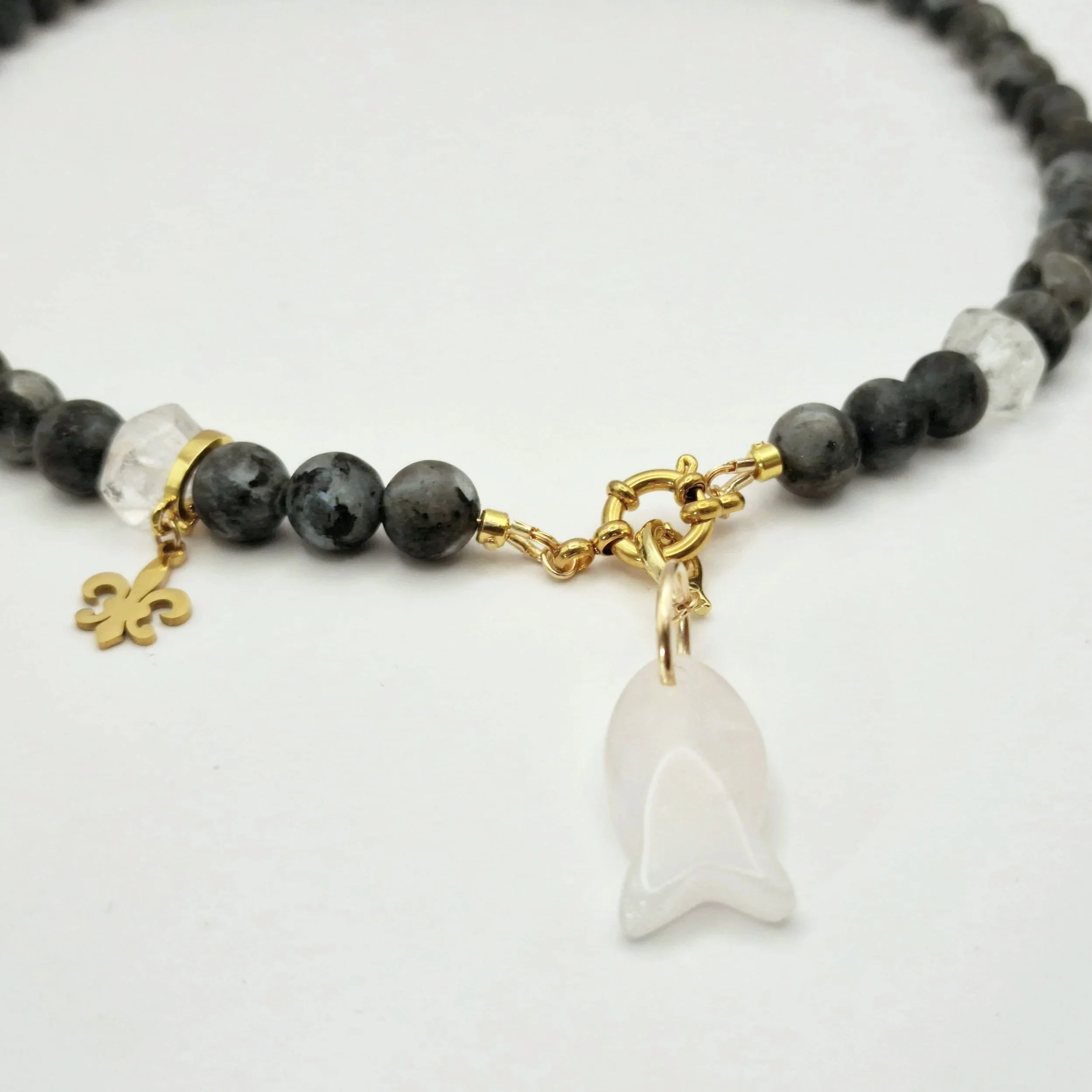 Kette aus Spektrolit, Bergkristall und Rosenquarzanhänger in Fischform mit vergoldetem Verschluss auf hellem Untergrund