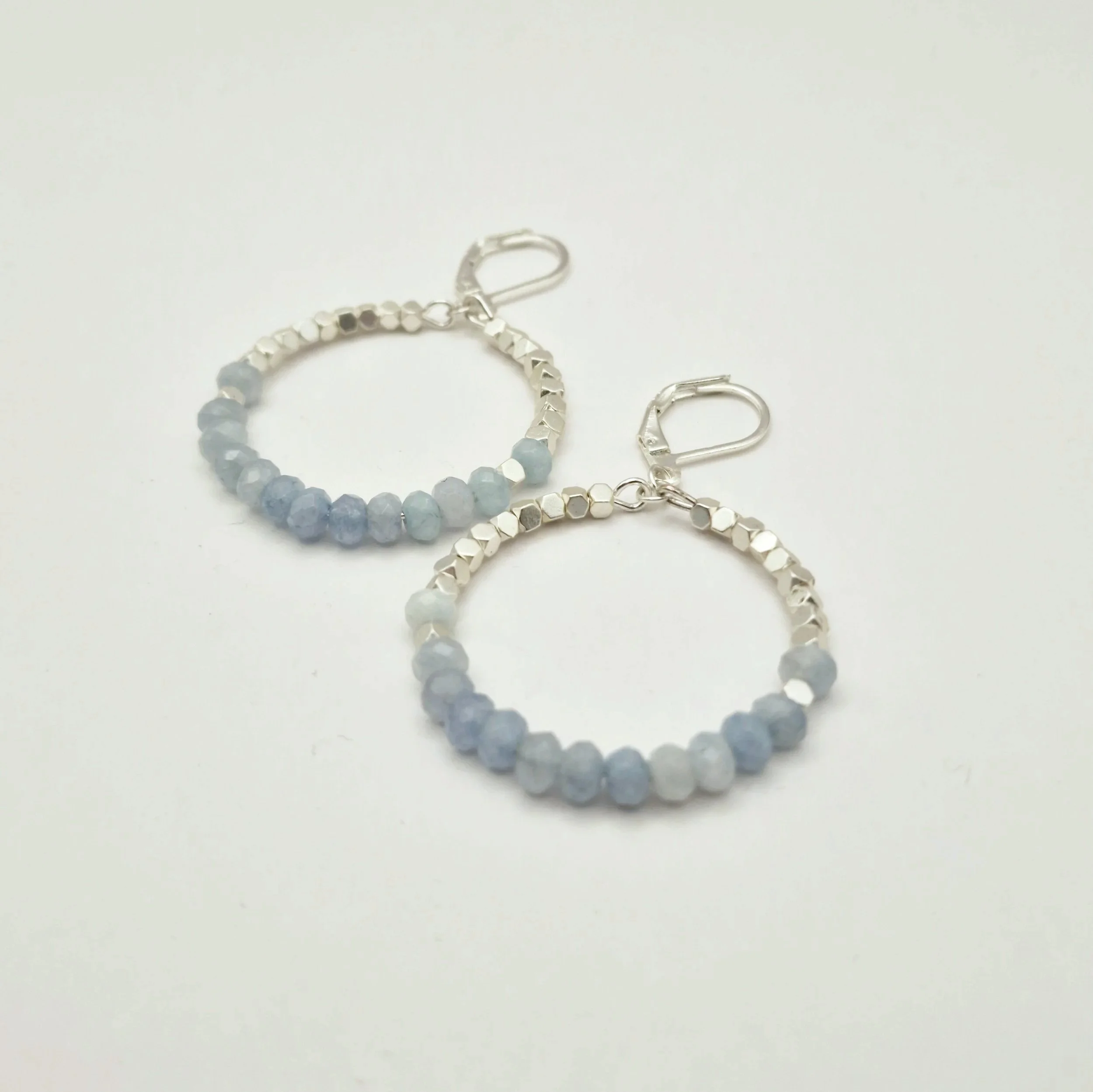 runde Hoop - Ohrringe in Silber mit weißvergoldetem Hämatit Perlen und facettierten Aquamarinperlen auf hellem Untergrund