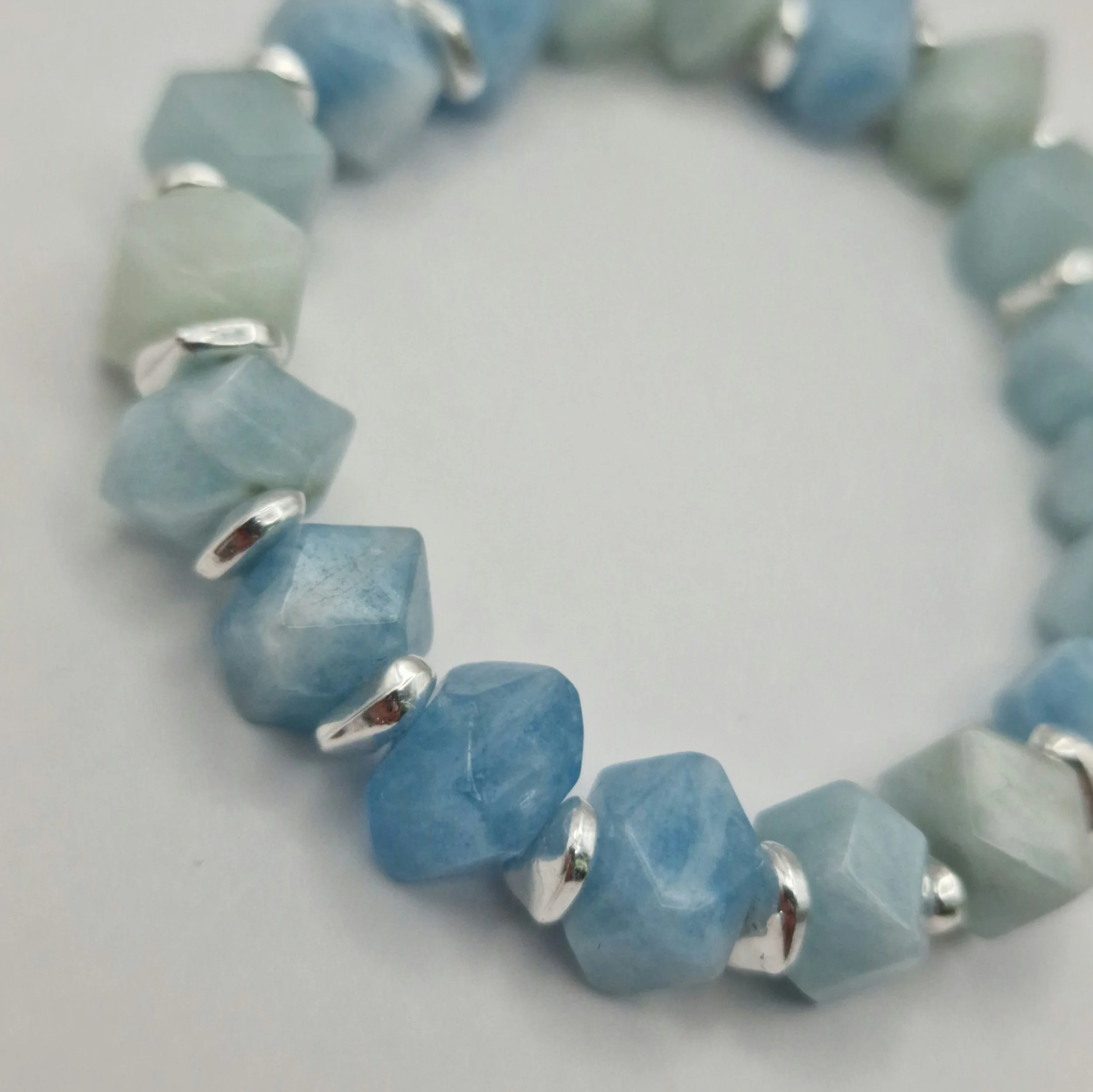 Armband aus unregelmäßigen blauen Aquamarin Perlen mit versilberten Spacern auf weißem Untergrund