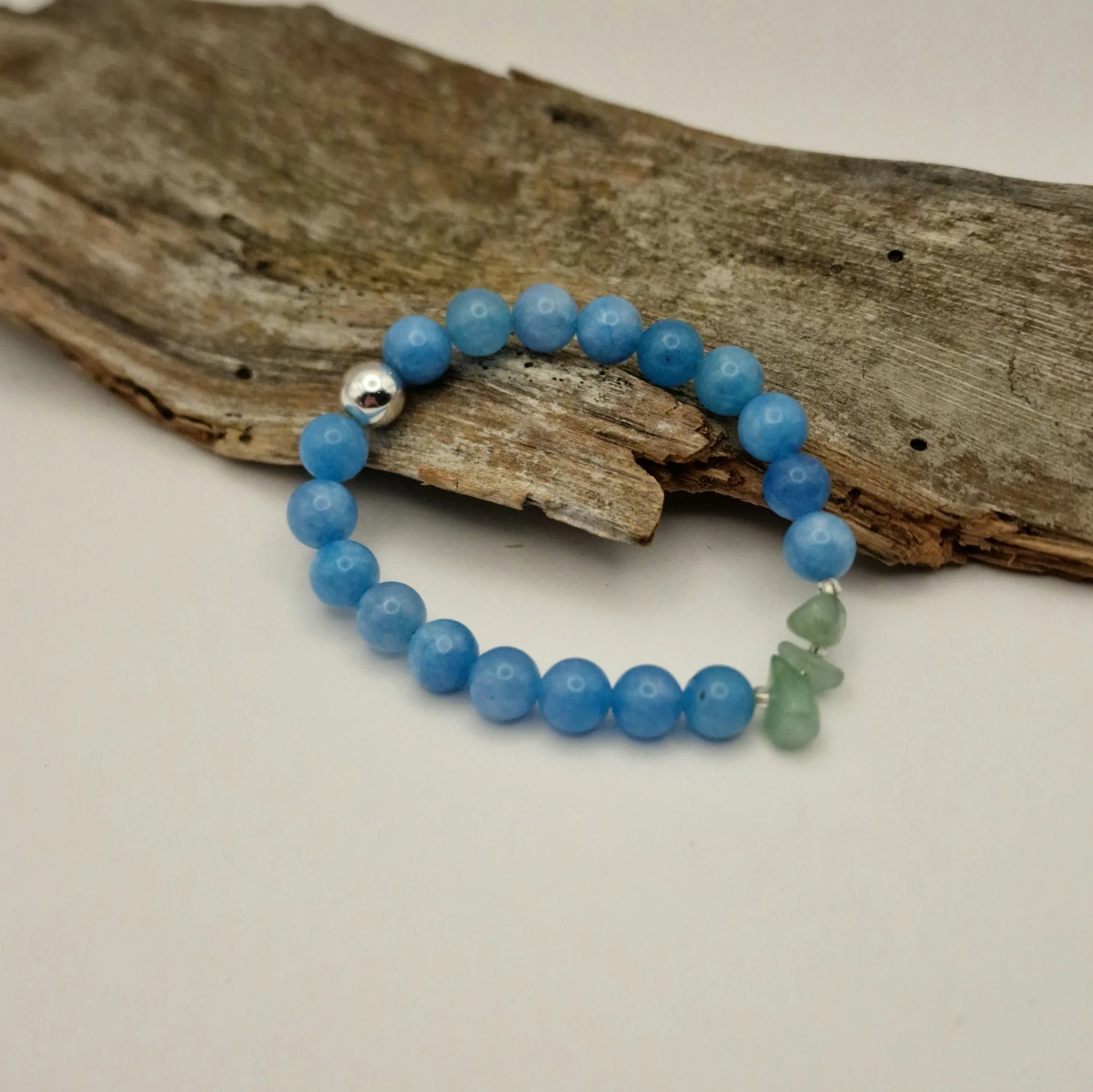 Armband aus blauen Aquamarinperlen mit Amazonitsplittern und einer versilberten Hämatit-Perle auf Treibholz und hellem Untergrund
