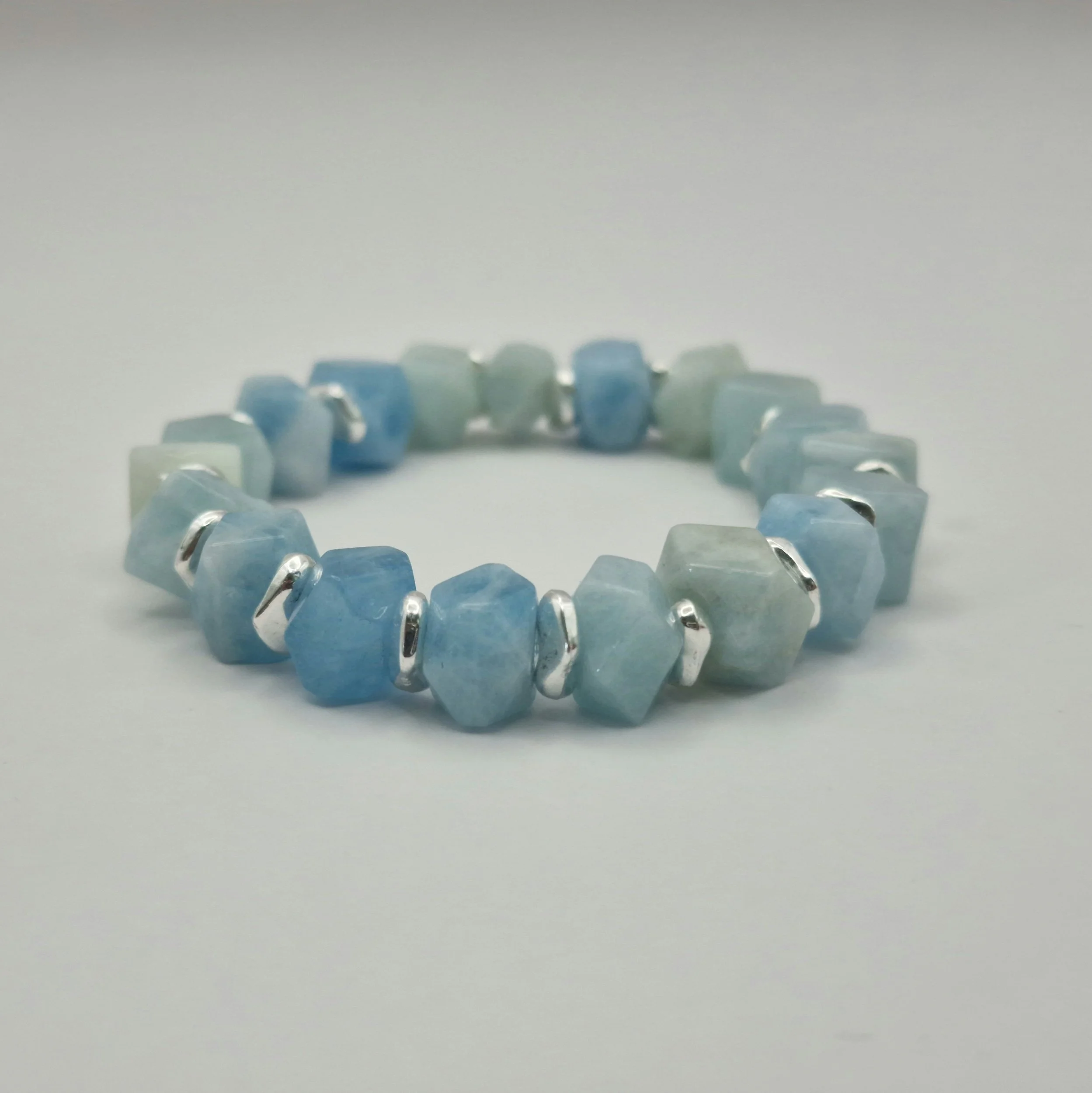 Armband aus unregelmäßigen blauen Aquamarin Perlen mit versilberten Spacern auf weißem Untergrund