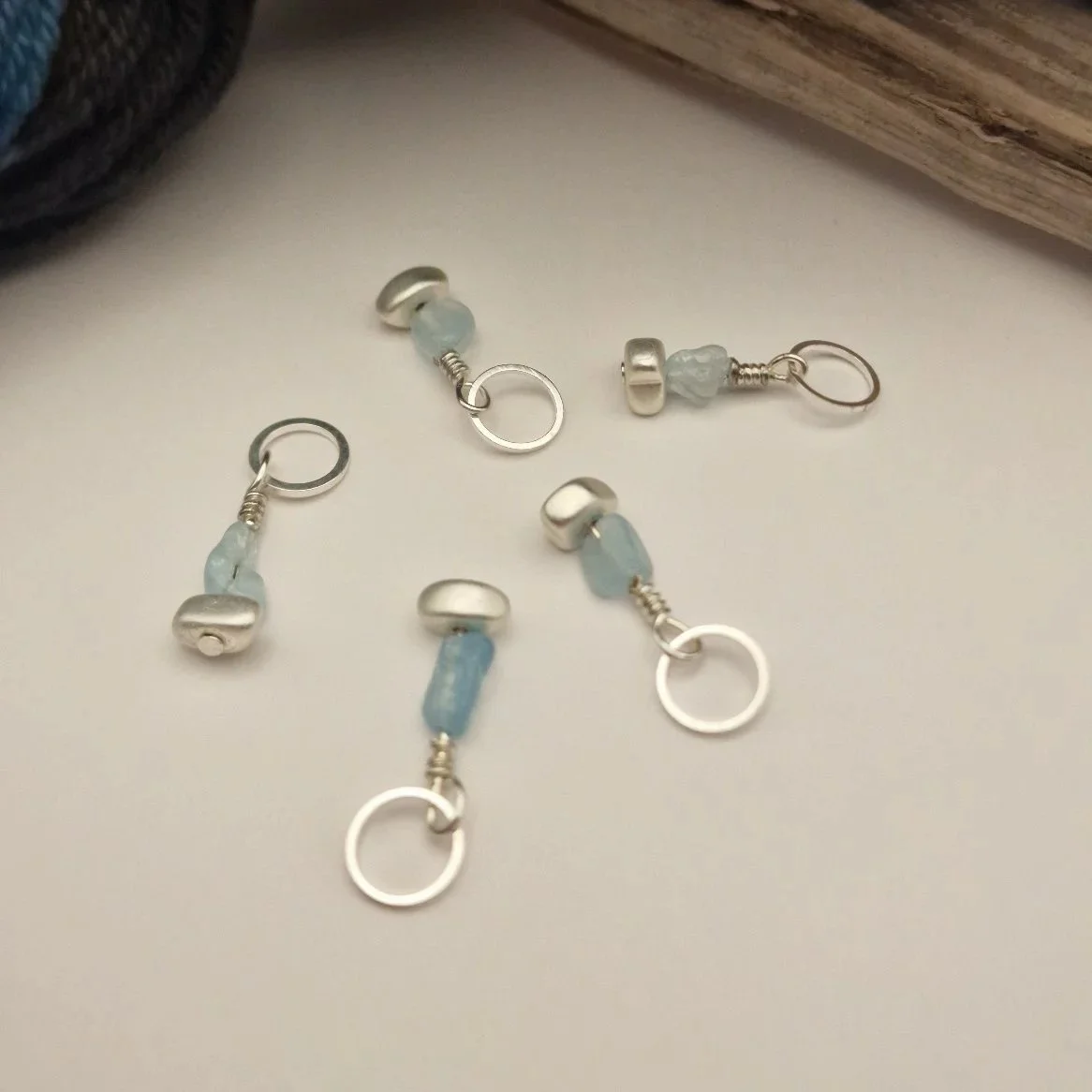 Set von 5 Maschenmarkierern mit Nuggets von Aquamarin und versilbertem matten Hämatit und versilberten Ringen auf weißem Untergrund