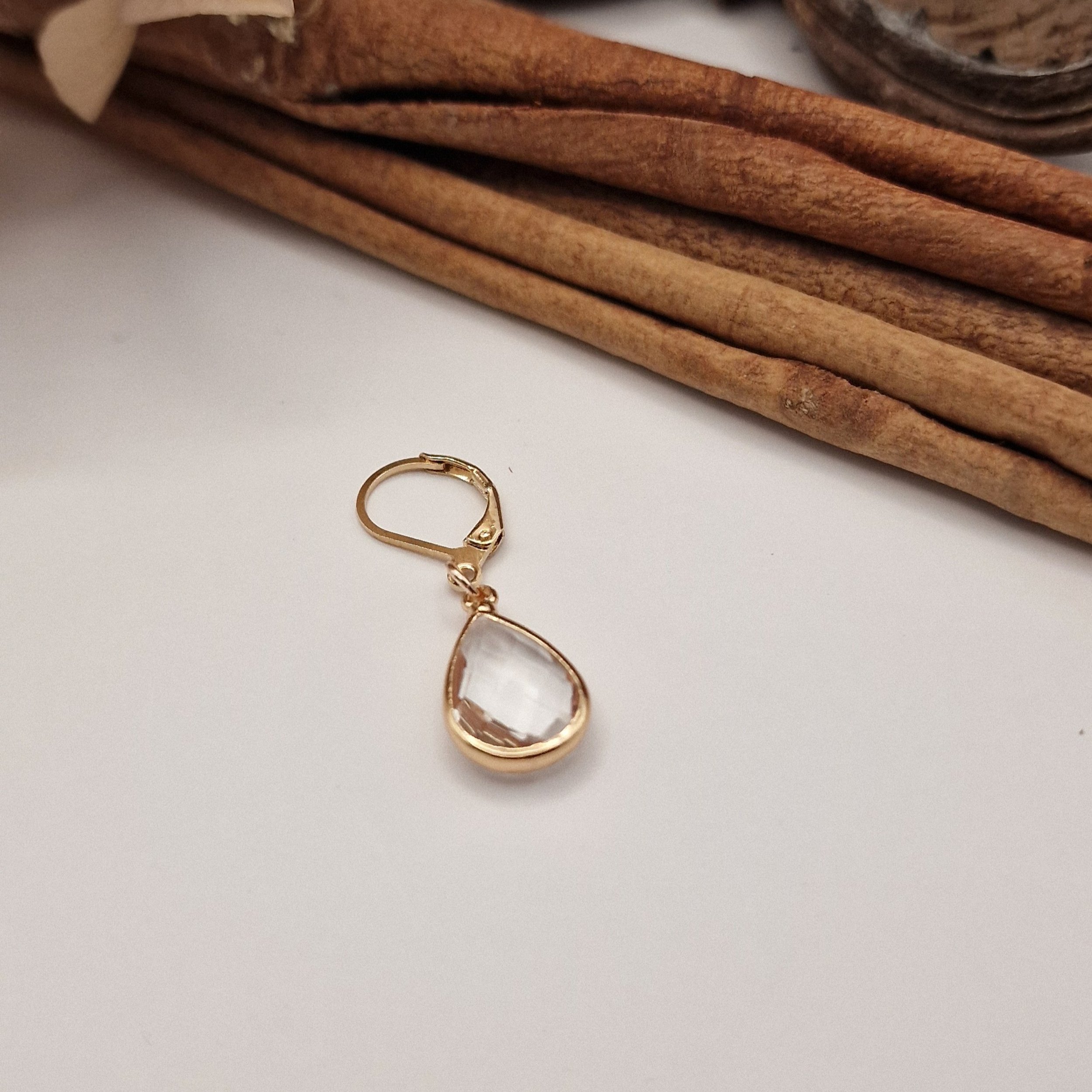 Eleganter Maschenmarkierer mit goldfarbenem Ring und geschliffenem, farblosem Glasanhänger in edler Goldfassung. Handgefertigt, filigran und ein Symbol für Klarheit und Präzision beim Stricken.