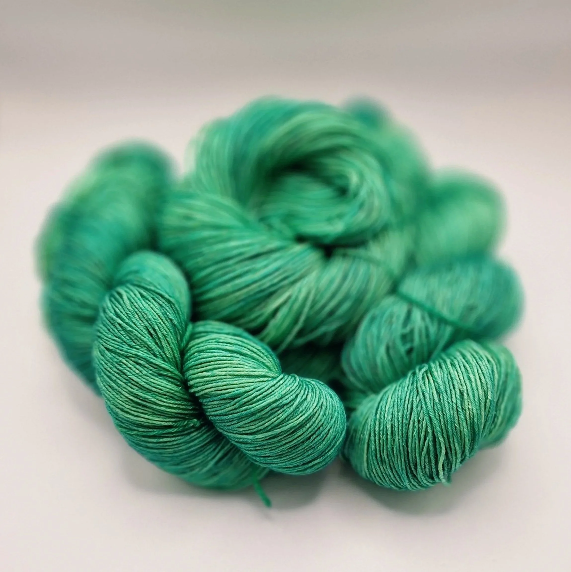 Tiefes Grün handgefärbt auf einem Strang Merino-Seiden-Wolle auf hellem Untergrund