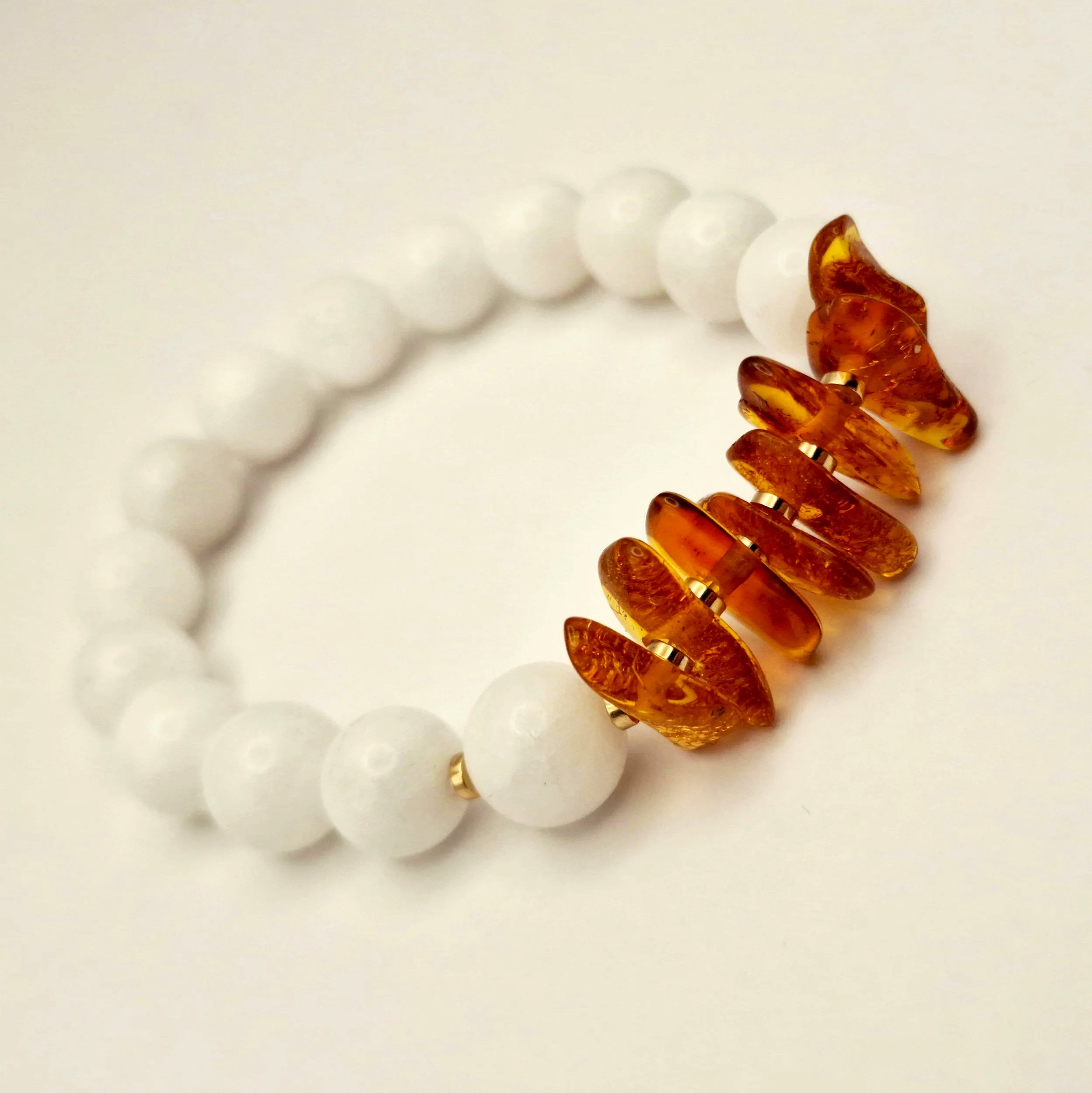 Armband aus weißen Perlen und Bernsteinsplittern auf hellem Untergrund