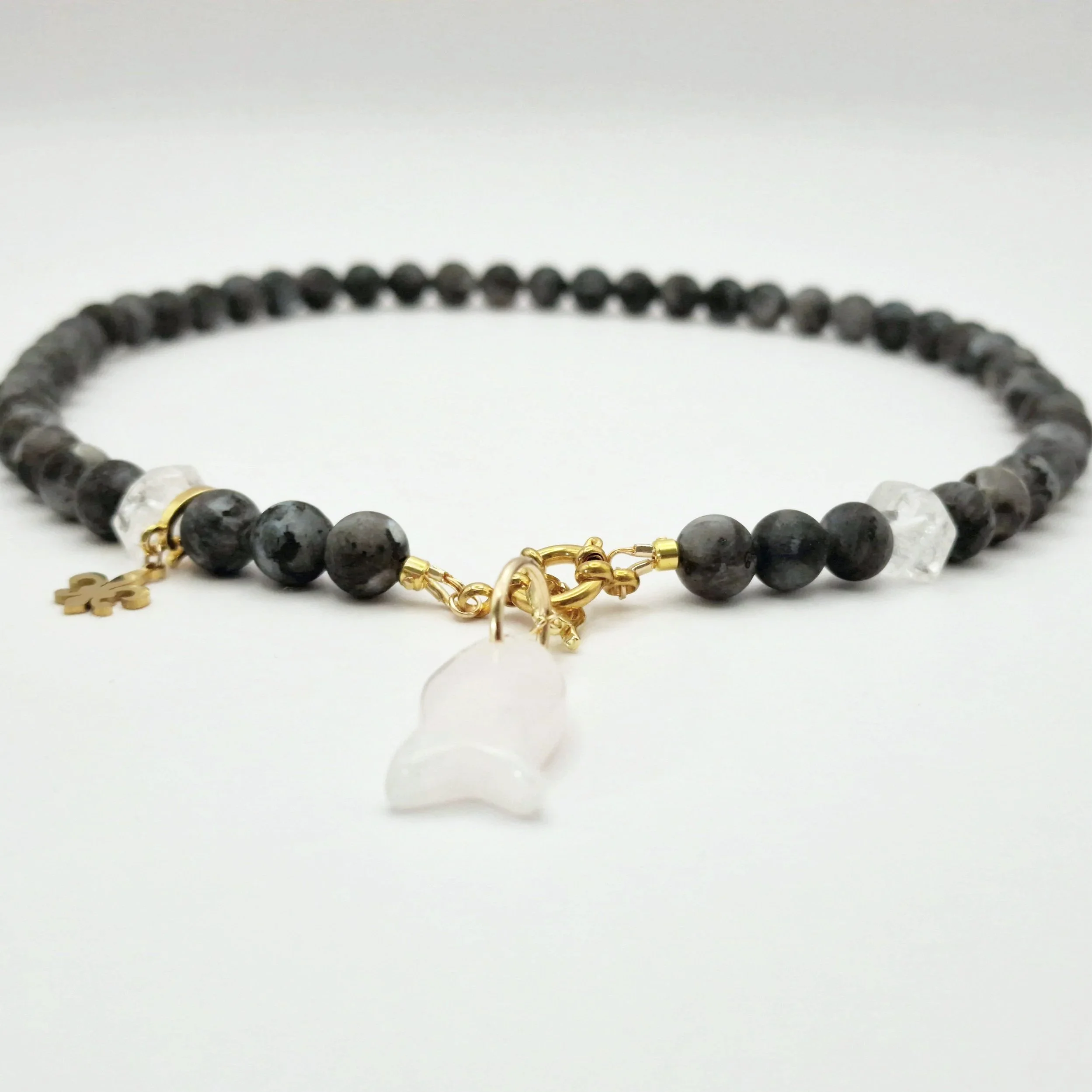 Kette aus Spektrolit, Bergkristall und Rosenquarzanhänger in Fischform mit vergoldetem Verschluss auf hellem Untergrund