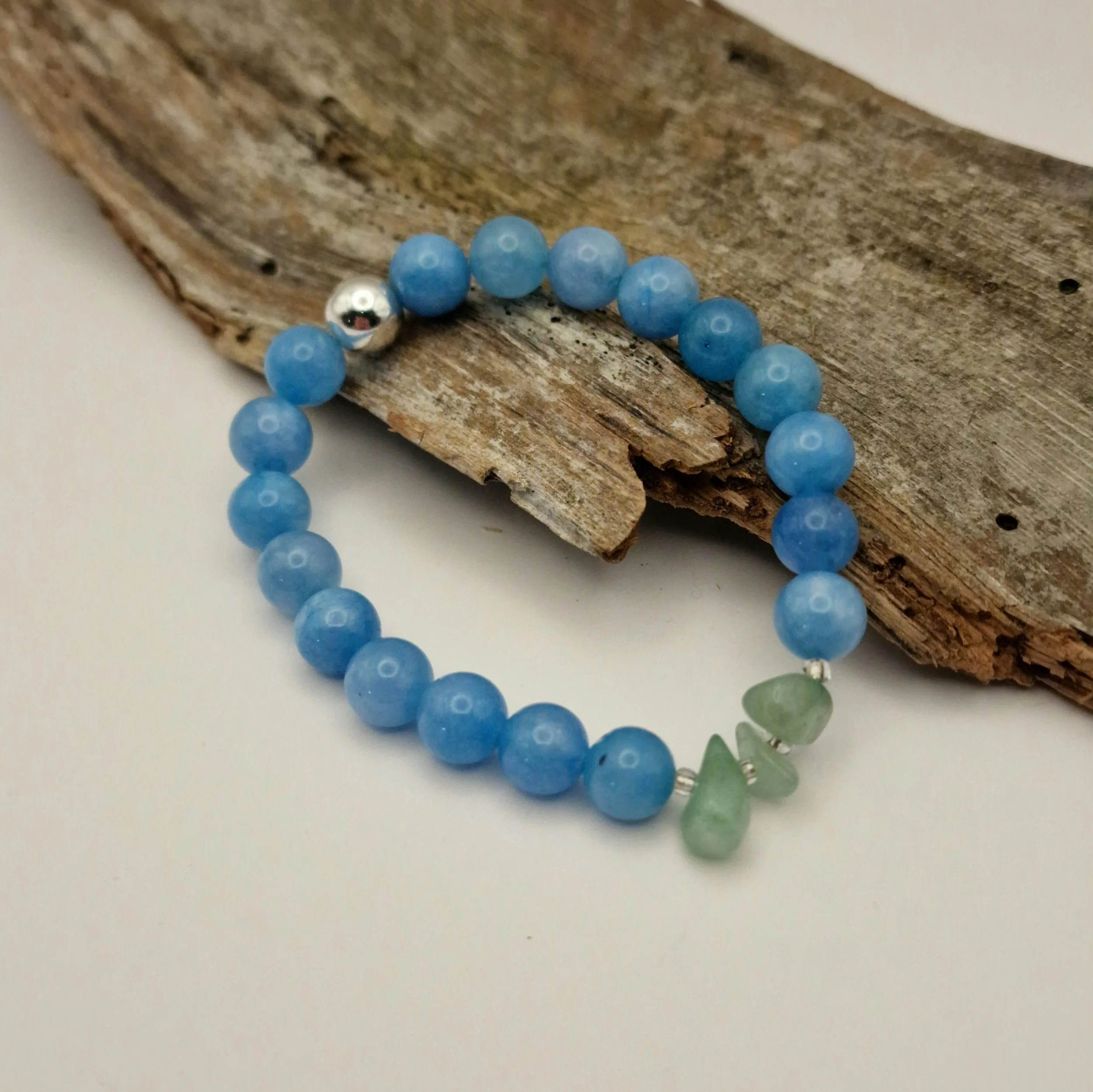 Armband aus blauen Aquamarinperlen mit Amazonitsplittern und einer versilberten Hämatit-Perle auf Treibholz und hellem Untergrund