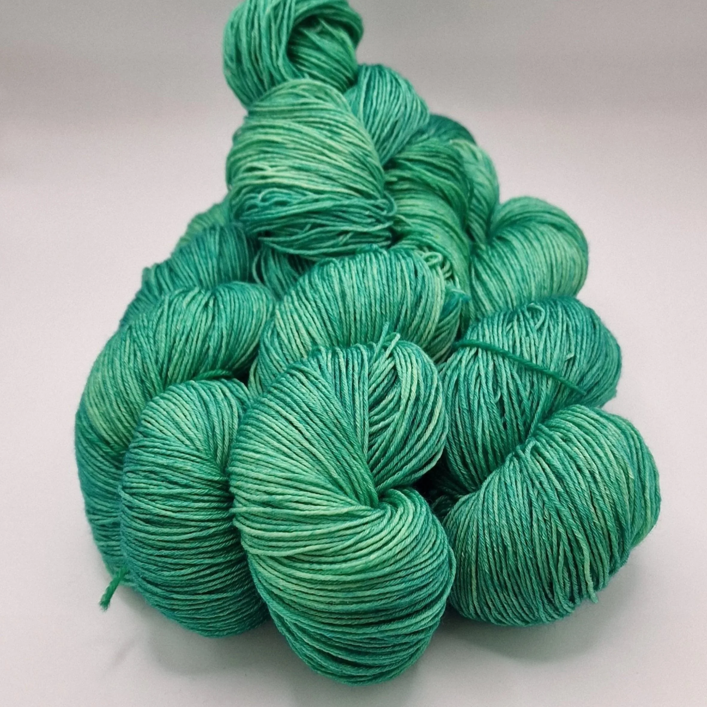 Tiefes Grün handgefärbt auf einem Strang Merino-Seiden-Wolle auf hellem Untergrund