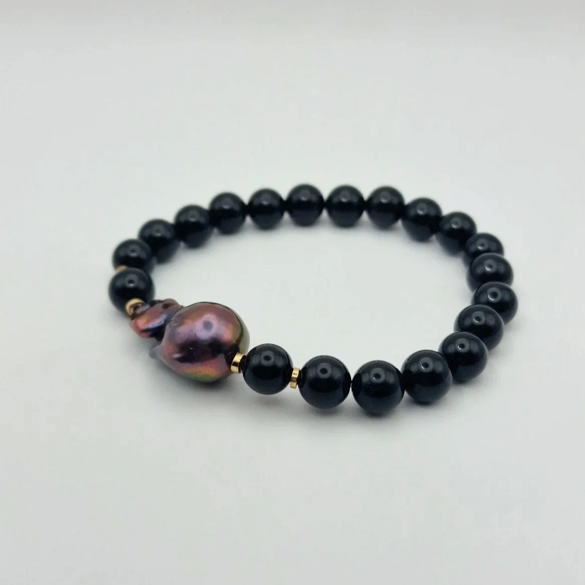 Armband aus tiefschwarzen Onyxperlen und einer violett schimmernden barocken Tahiti - Perle