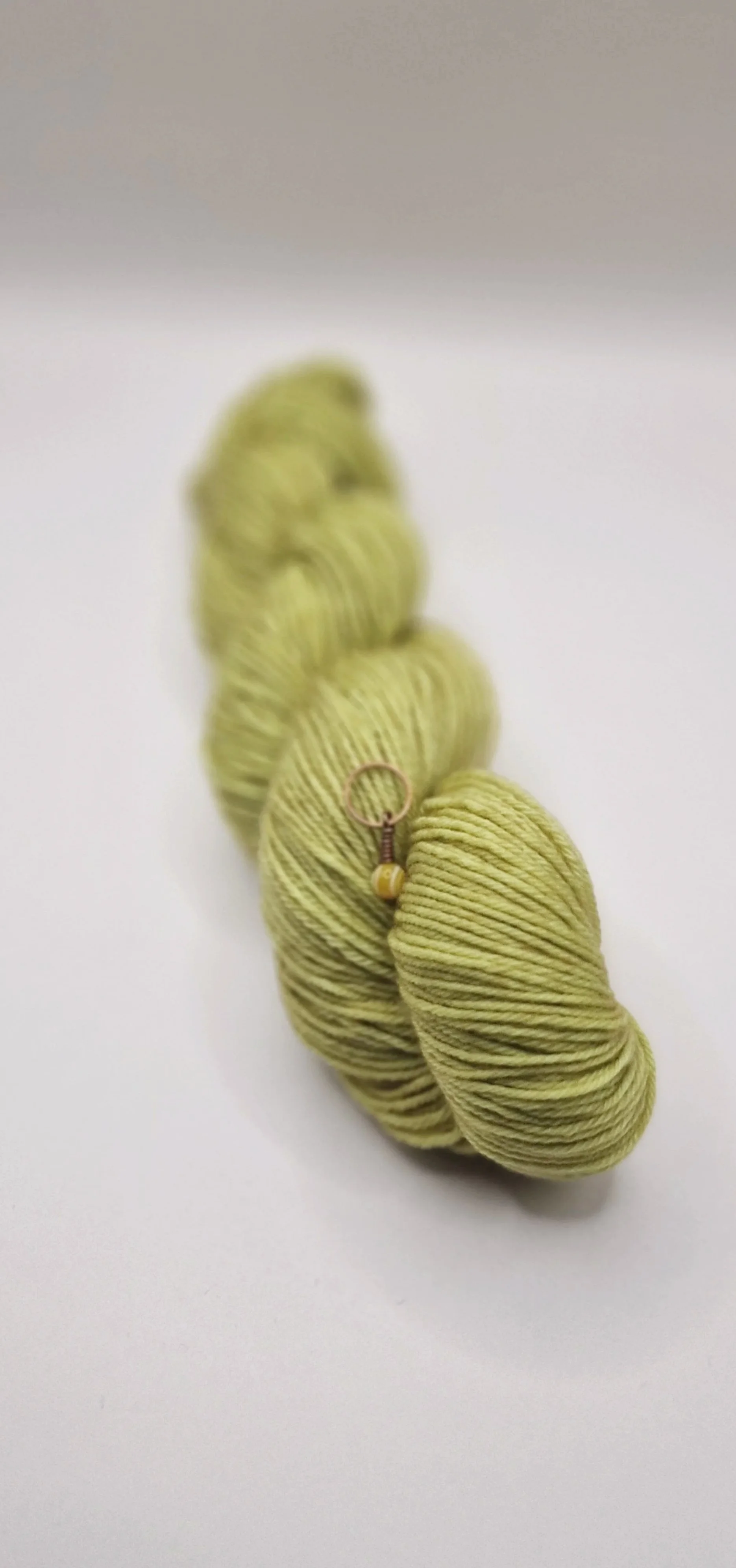 ein Strang goldgrünes Kaschmirmischgarn auf hellem Untergrund