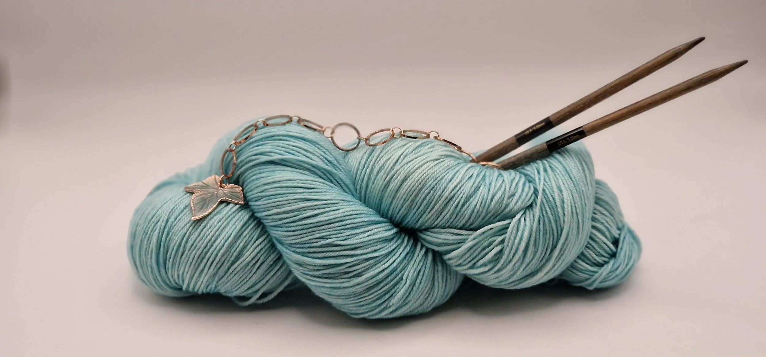 semisolid gefärbtes Garn in hellem Teal mit Holzstricknadeln