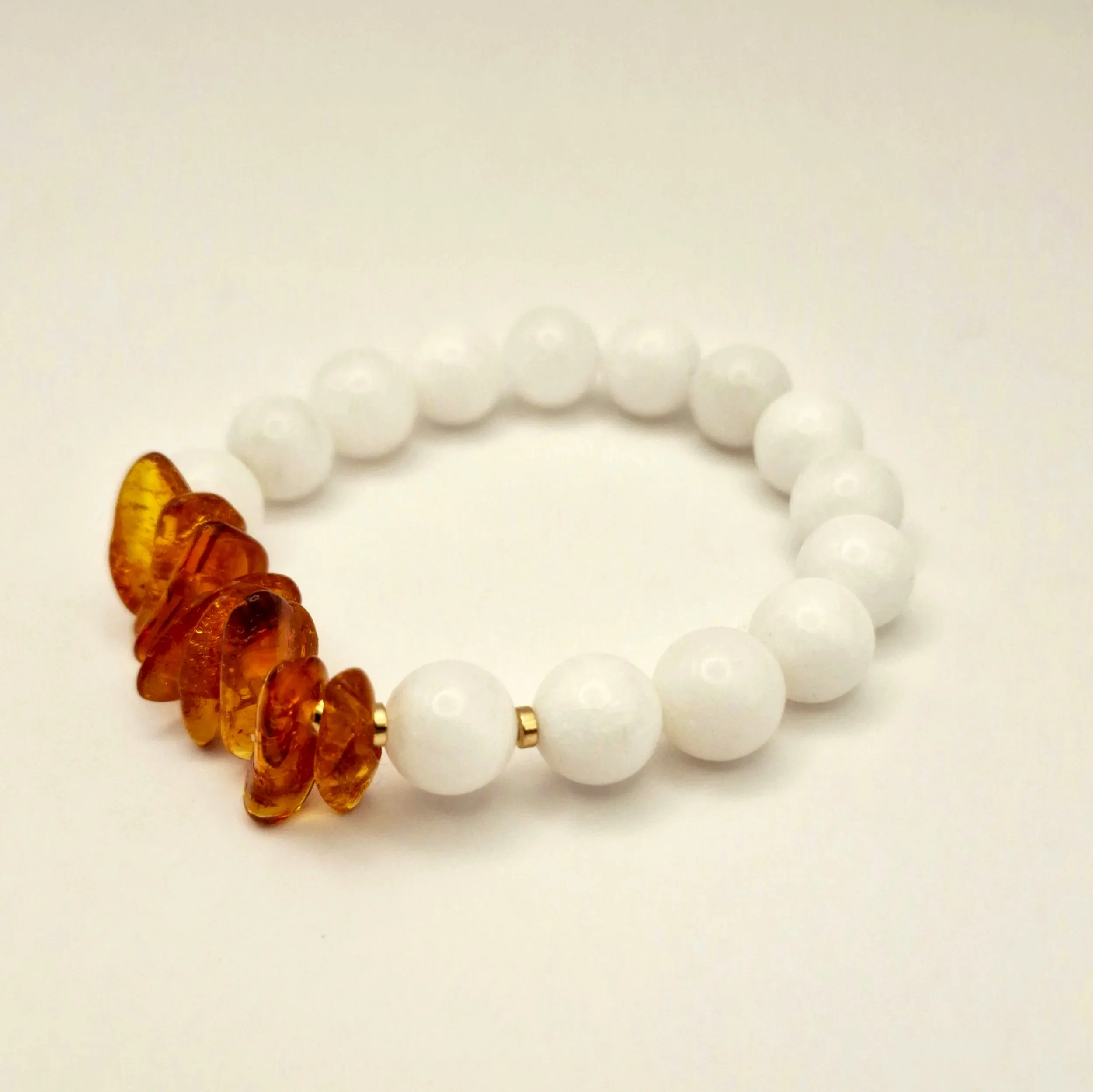 Armband aus weißen Perlen und Bernsteinsplittern auf hellem Untergrund