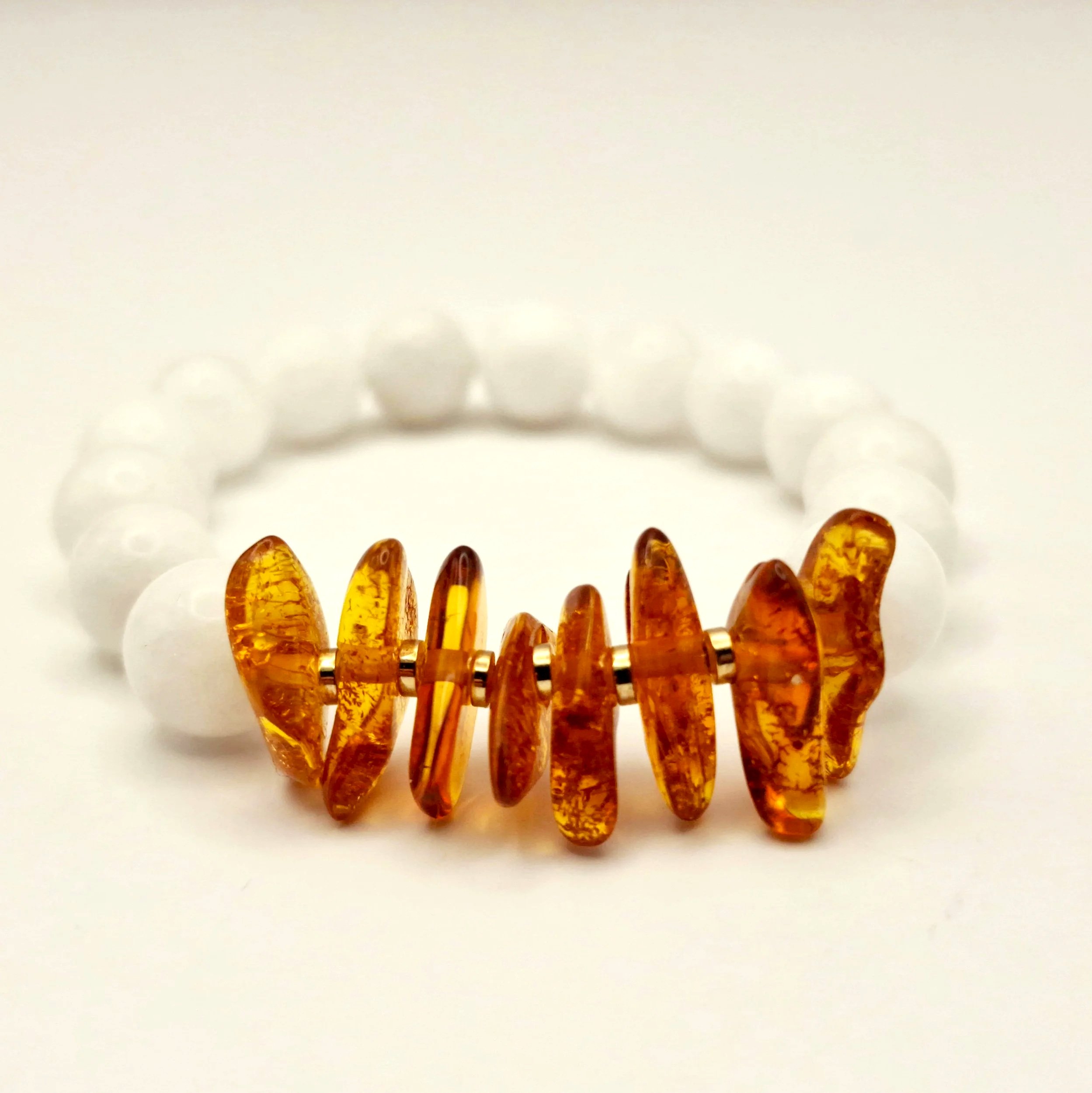 Armband aus weißen Perlen und Bernsteinsplittern auf hellem Untergrund