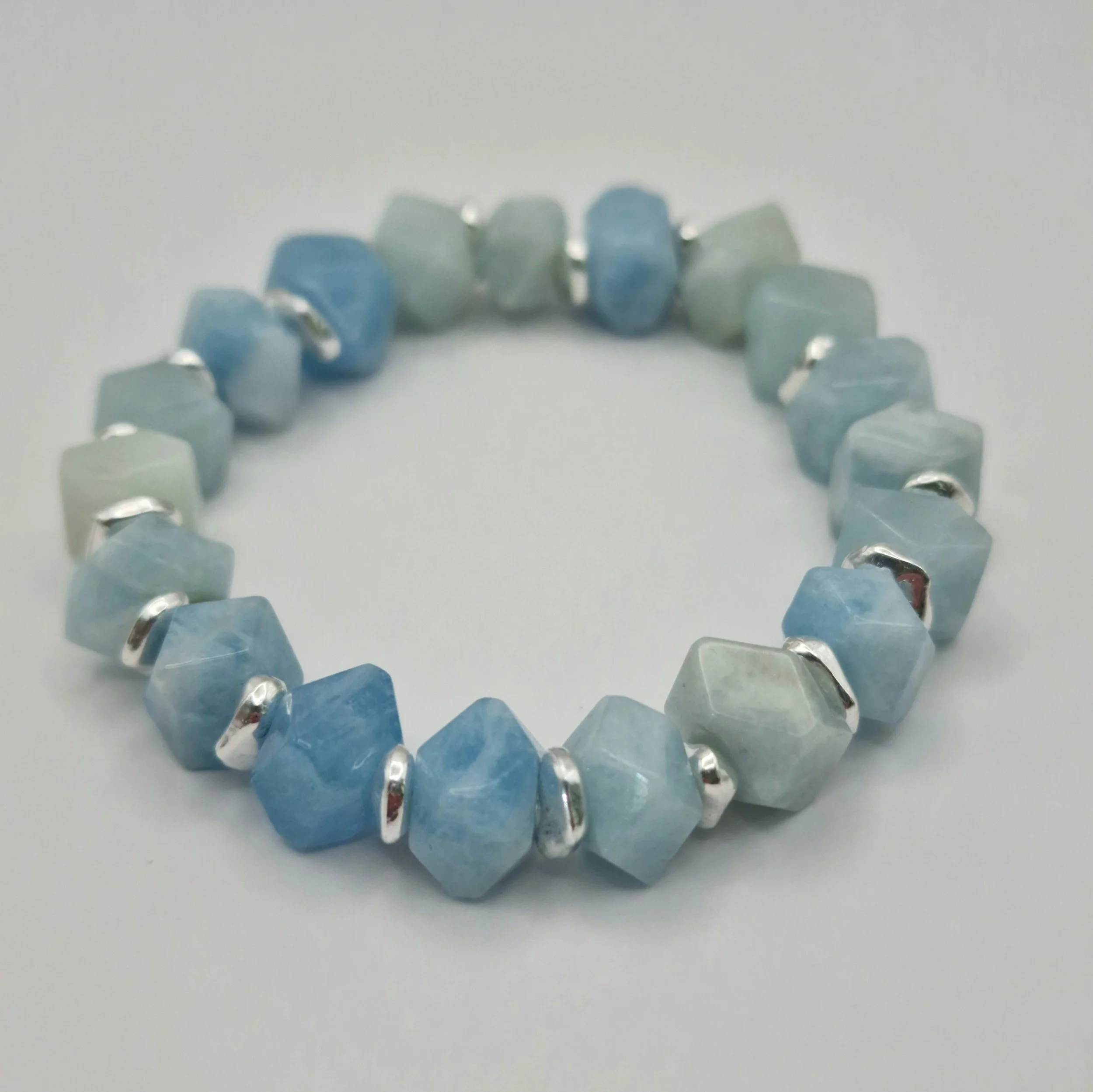 Armband aus unregelmäßigen blauen Aquamarin Perlen mit versilberten Spacern auf weißem Untergrund