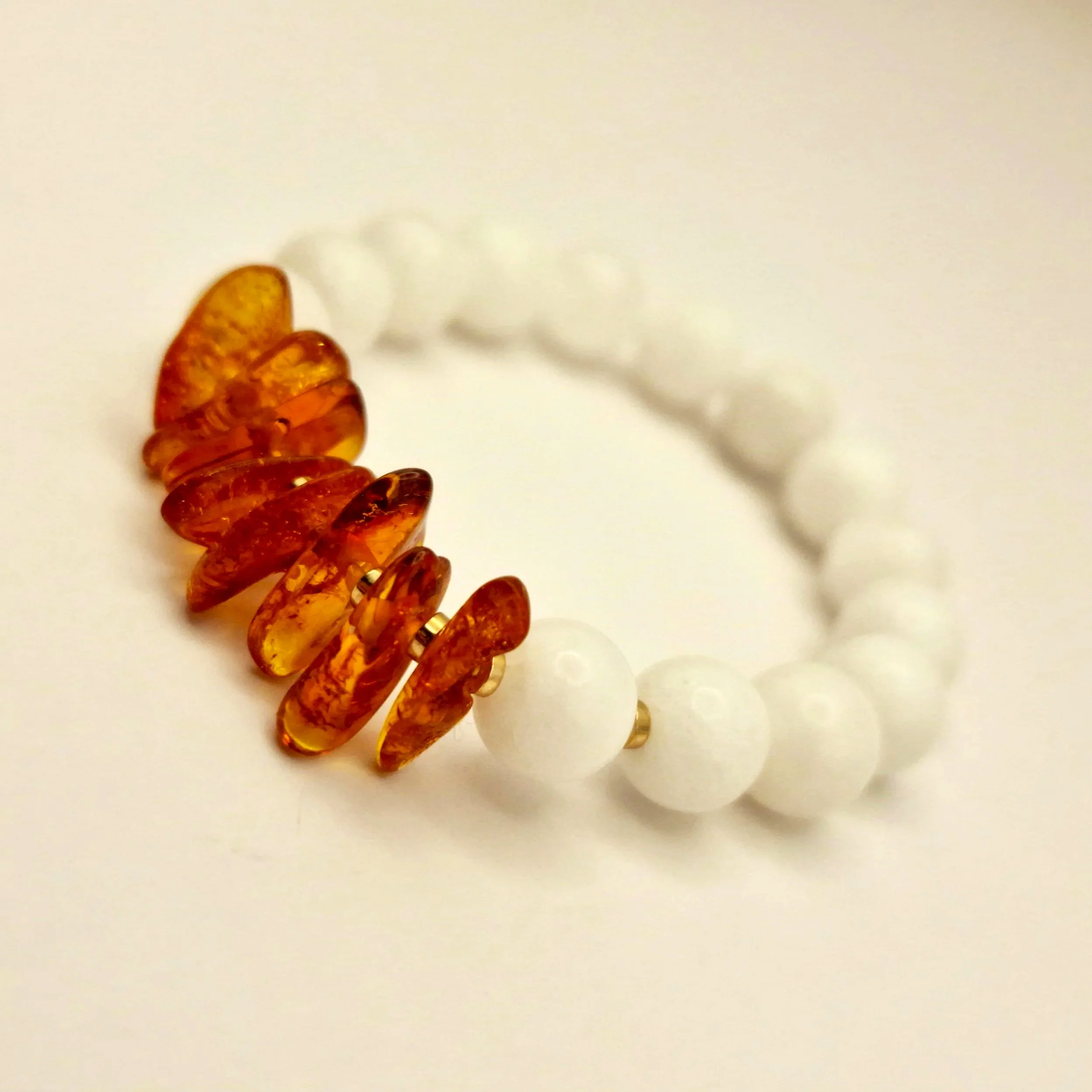 Armband aus weißen Perlen und Bernsteinsplittern auf hellem Untergrund