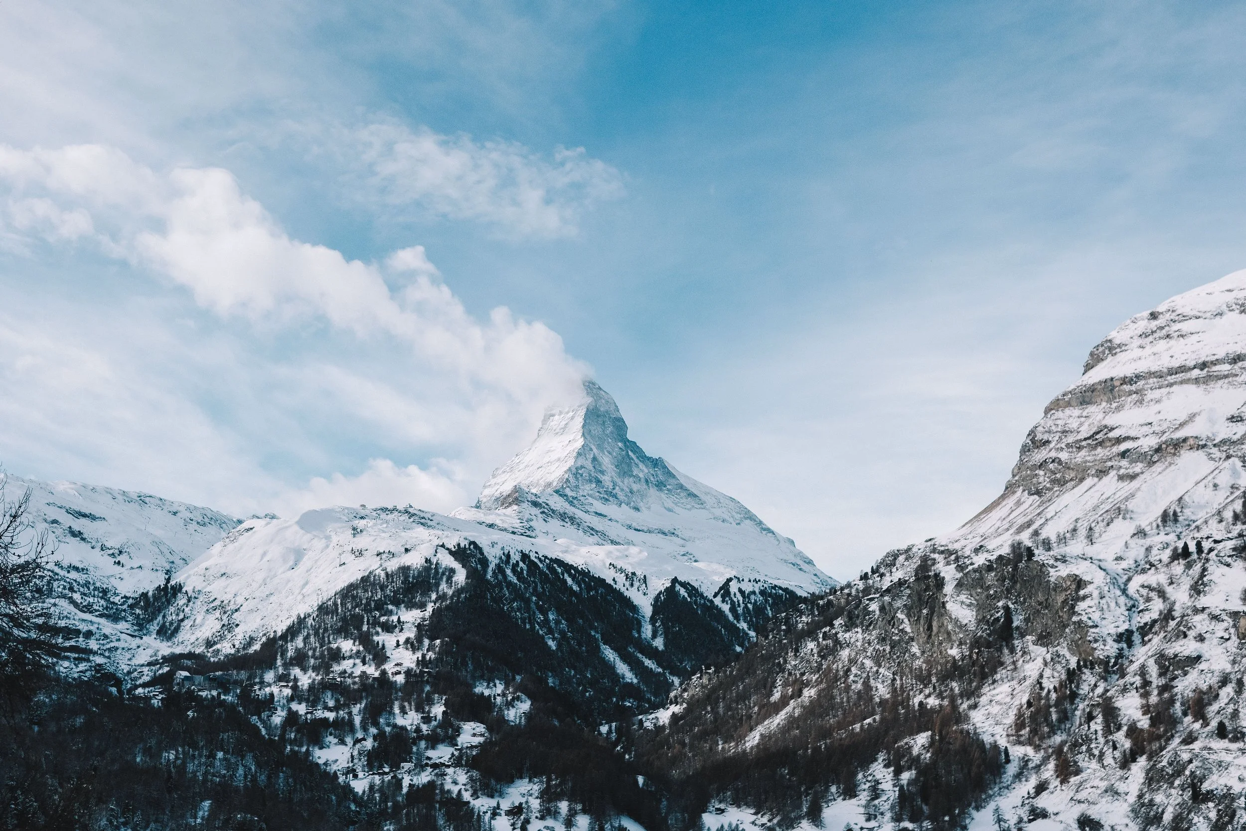 Snow-covered mountain peak, blue sky, scattered clouds.