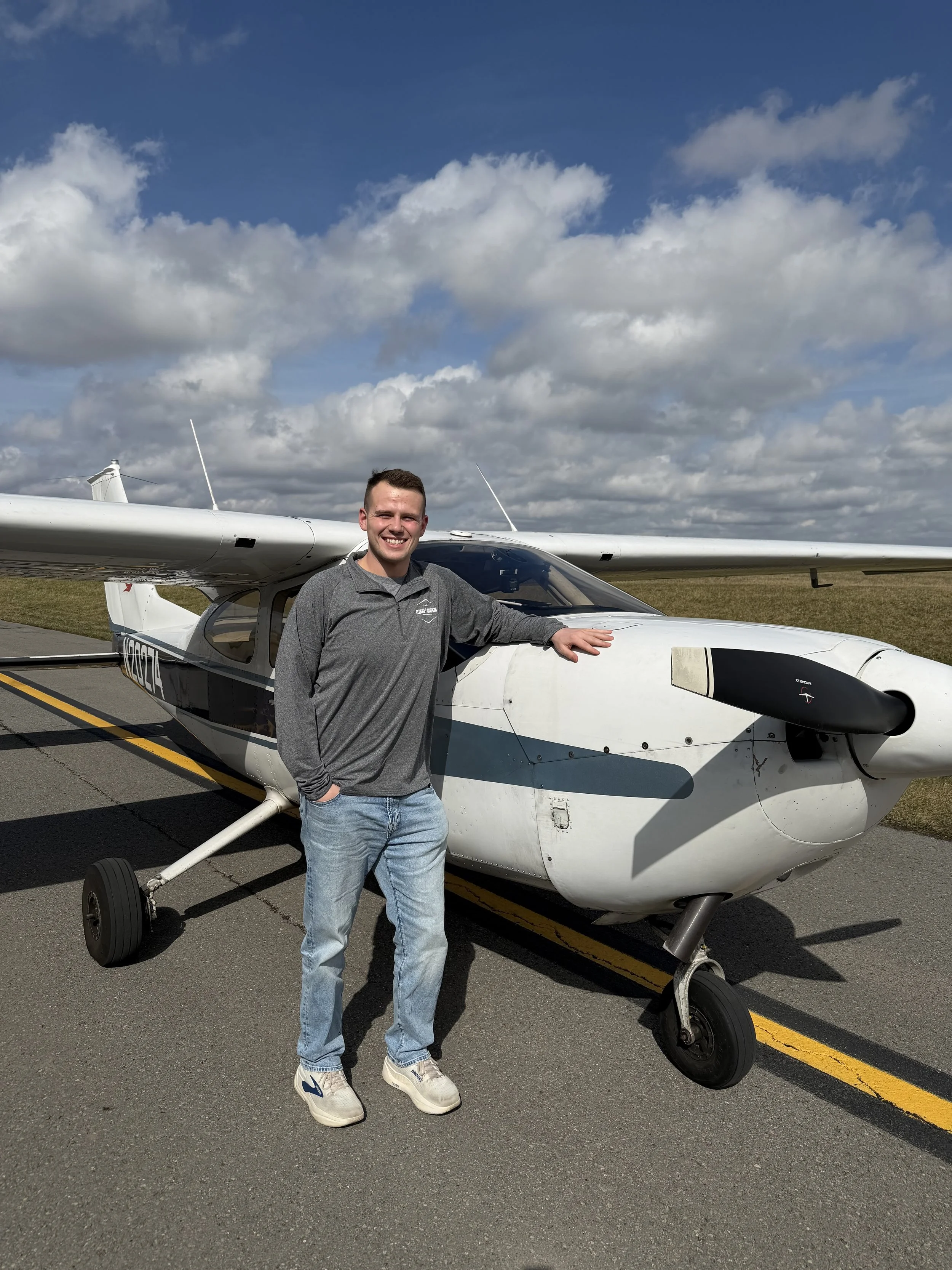 Person standing next to a lime green single-engine airplane on a tarmac under a cloudy sky.