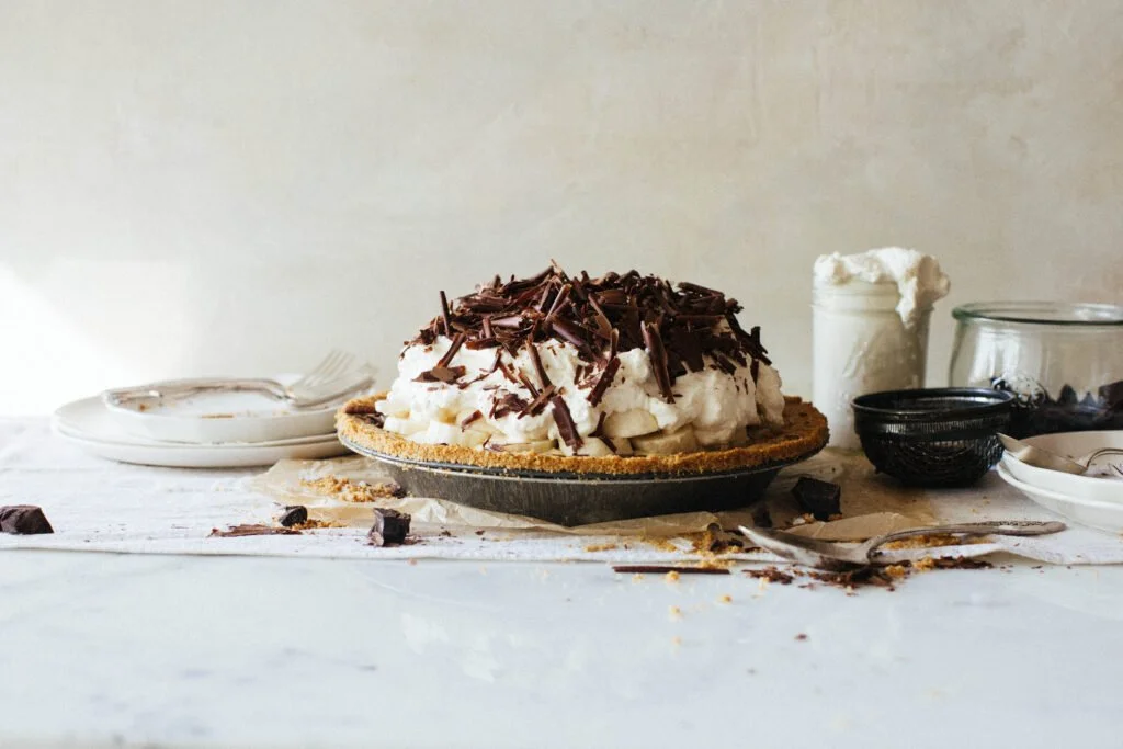 side view of banana cream pie piled high with whipped cream and chocolate shavings on top