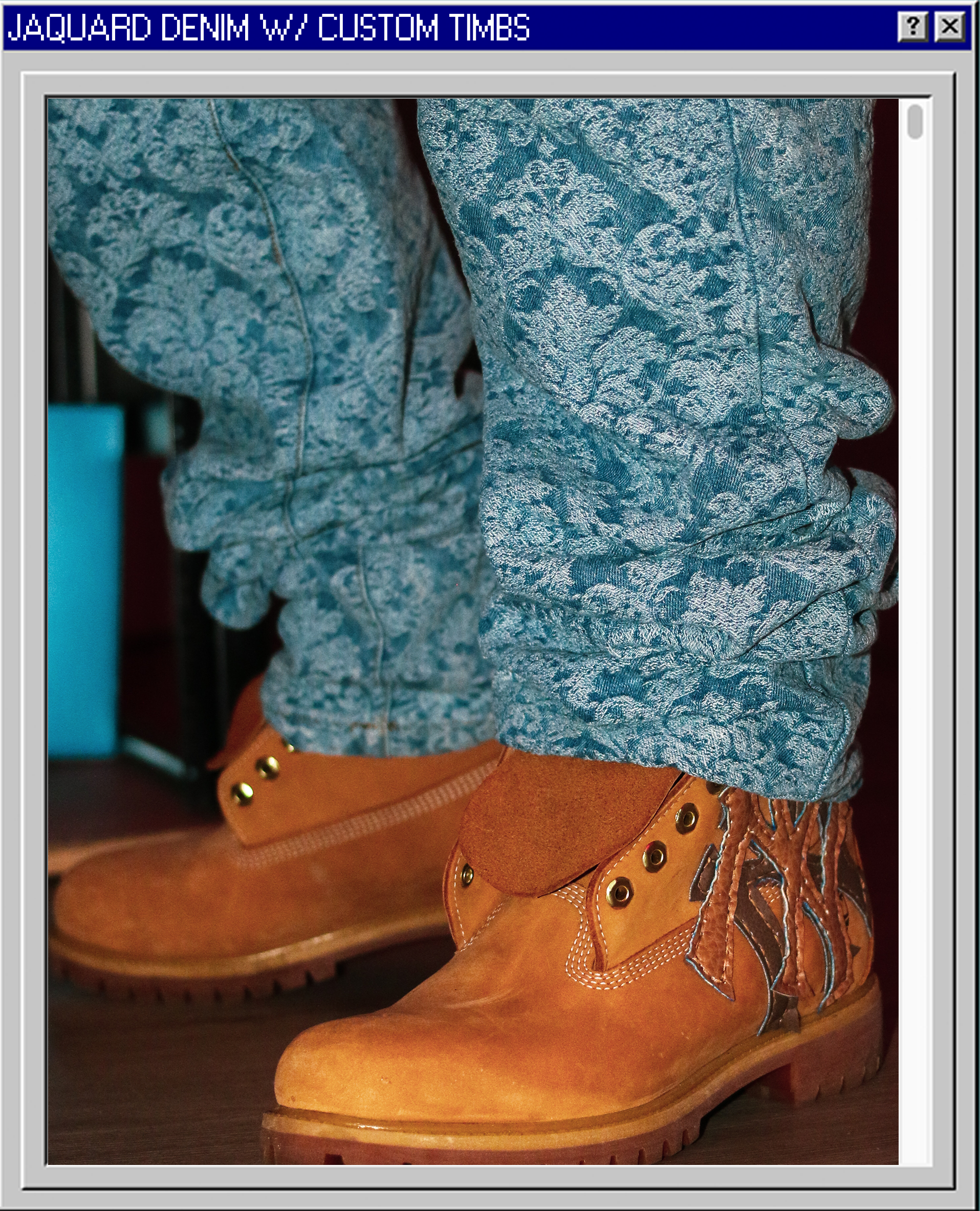 Close-up of tan work boots with gold eyelets and brown laces, worn with blue textured denim jeans.