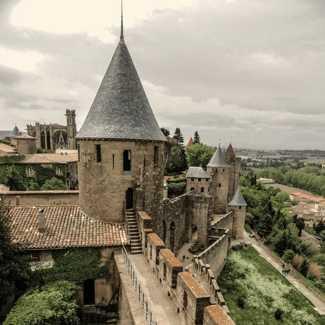 Close-up architectural detail of the medieval turrets and stone walls in Carcassonne, France; an immersive French heritage experience designed by Denise Kubica.