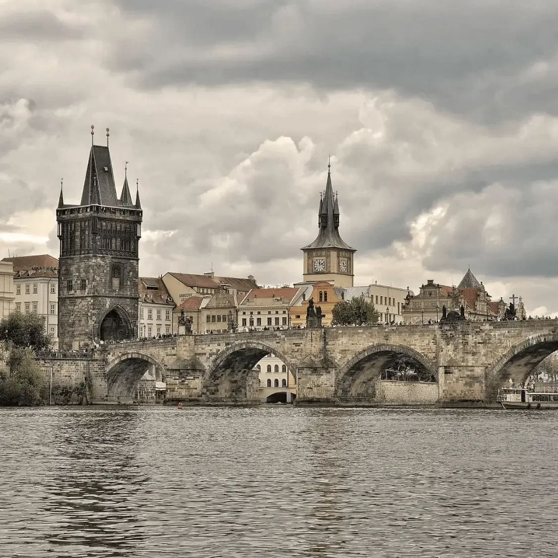 The Old Town Bridge Tower and Charles Bridge in Prague under a dramatic overcast sky; curated as part of a Central Europe luxury itinerary by Mindset Travel.