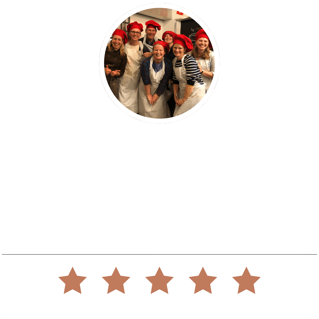 Group of people wearing red chef hats and aprons at a chocolate making class in Lucerne, Switzerland, smiling and having fun.