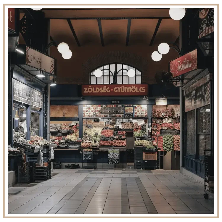 A view down an aisle at the Great Market Hall in Budapest, Hungary. At the end is a produce stand with a sign above it in Hungarian.