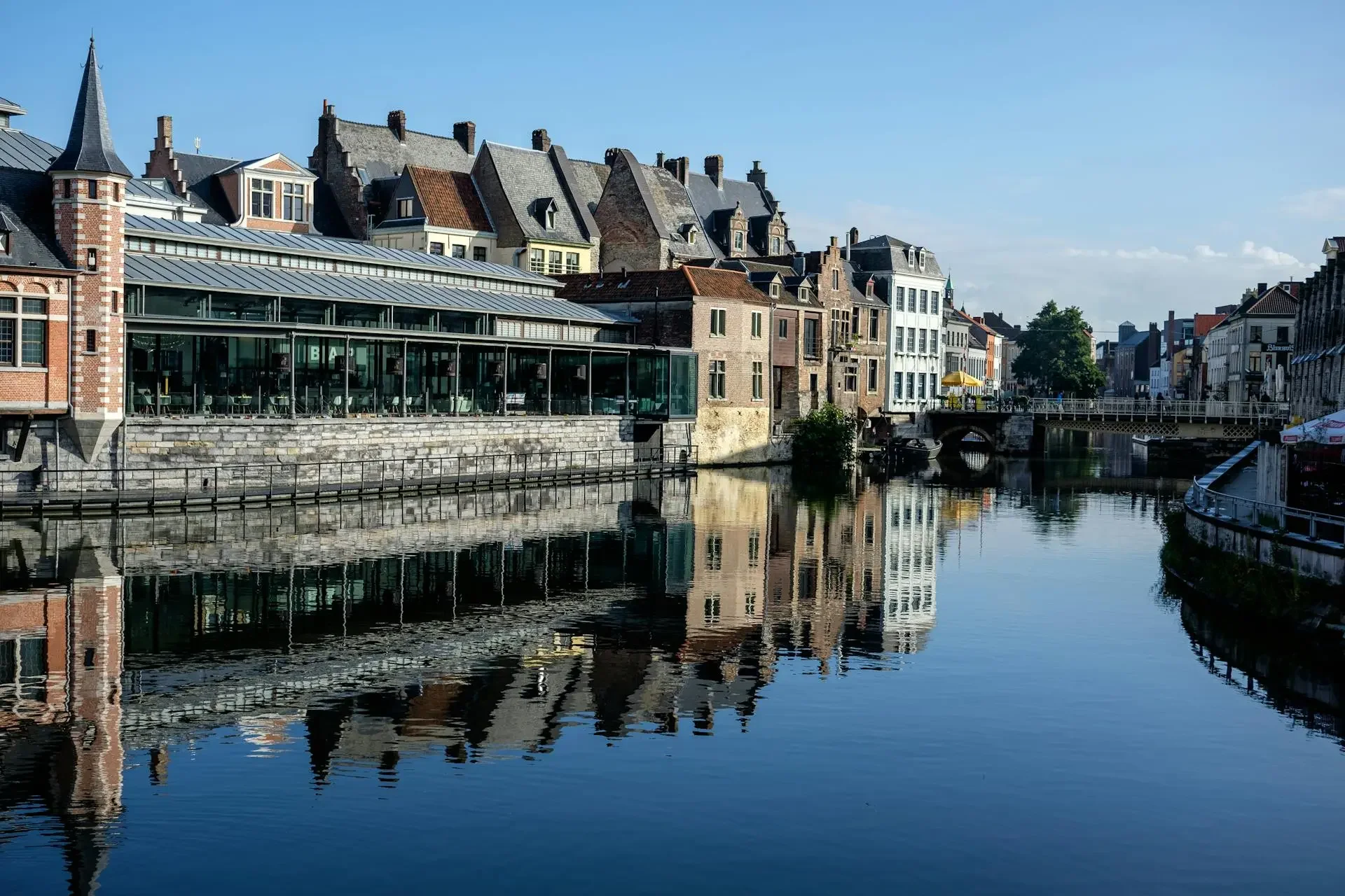 Reflection of historic buildings along the canal in Ghent, Belgium's Graslei quay