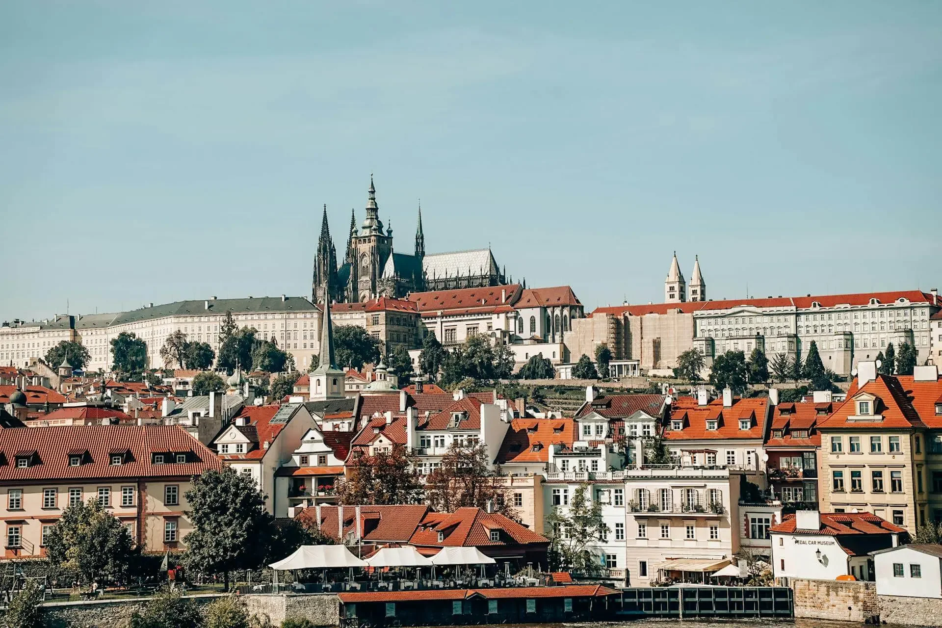 A daylight perspective of the Malá Strana district's rooftops leading up to the massive Gothic and Romanesque structures of Prague Castle.