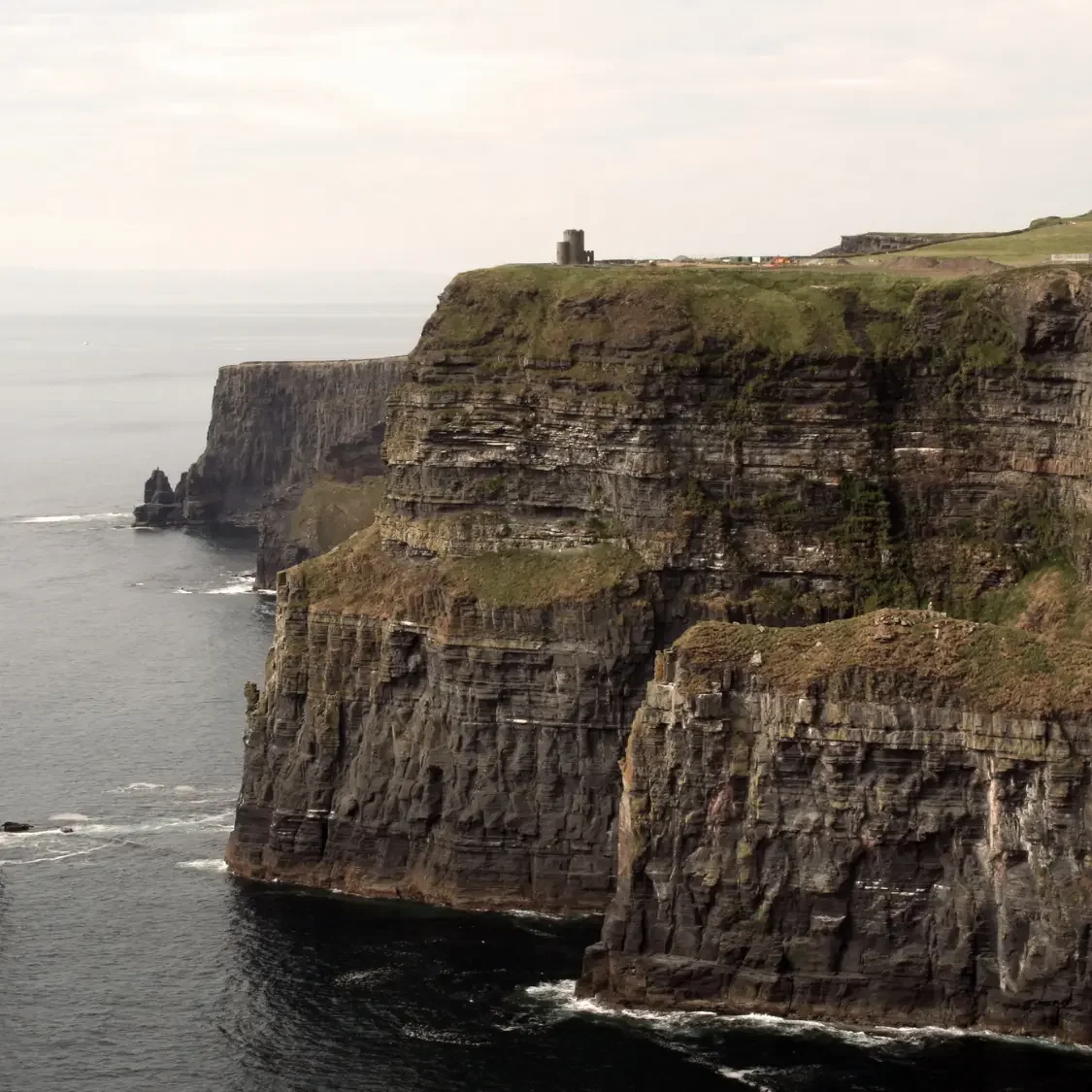 Moody evening view of O'Brien's Tower atop the Cliffs of Moher; a signature destination in a bespoke Ireland and Scotland travel itinerary by Denise Kubica.