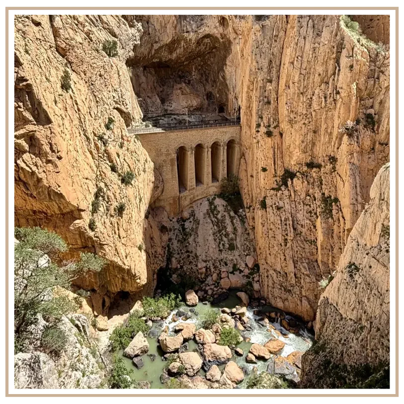 Take in the dramatic view looking down into the limestone cliffs of Gaitanes Gorge along the Caminito del Rey in Málaga, Spain, featuring the historic railway aqueduct bridge over the Guadalhorce River. Custom Southern Spain itinerary design by Minds